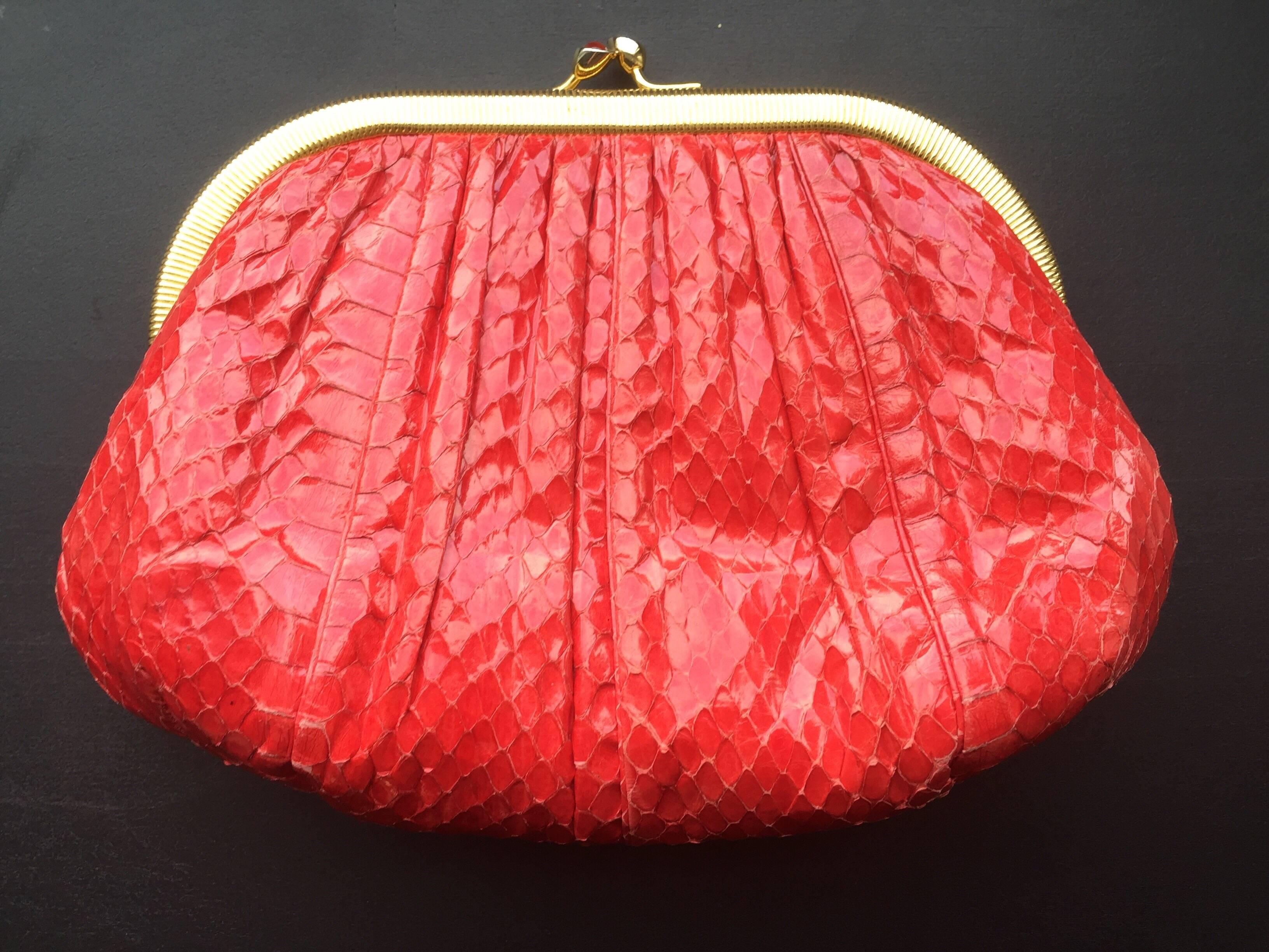 This Judith Leiber clutch is from the early 1980s.  This snakeskin clutch features gold hardware, snap closure, and an optional gold chain shoulder strap. The inside has a silk lining and small zipper pocket. The piece can be used as a shoulder bag