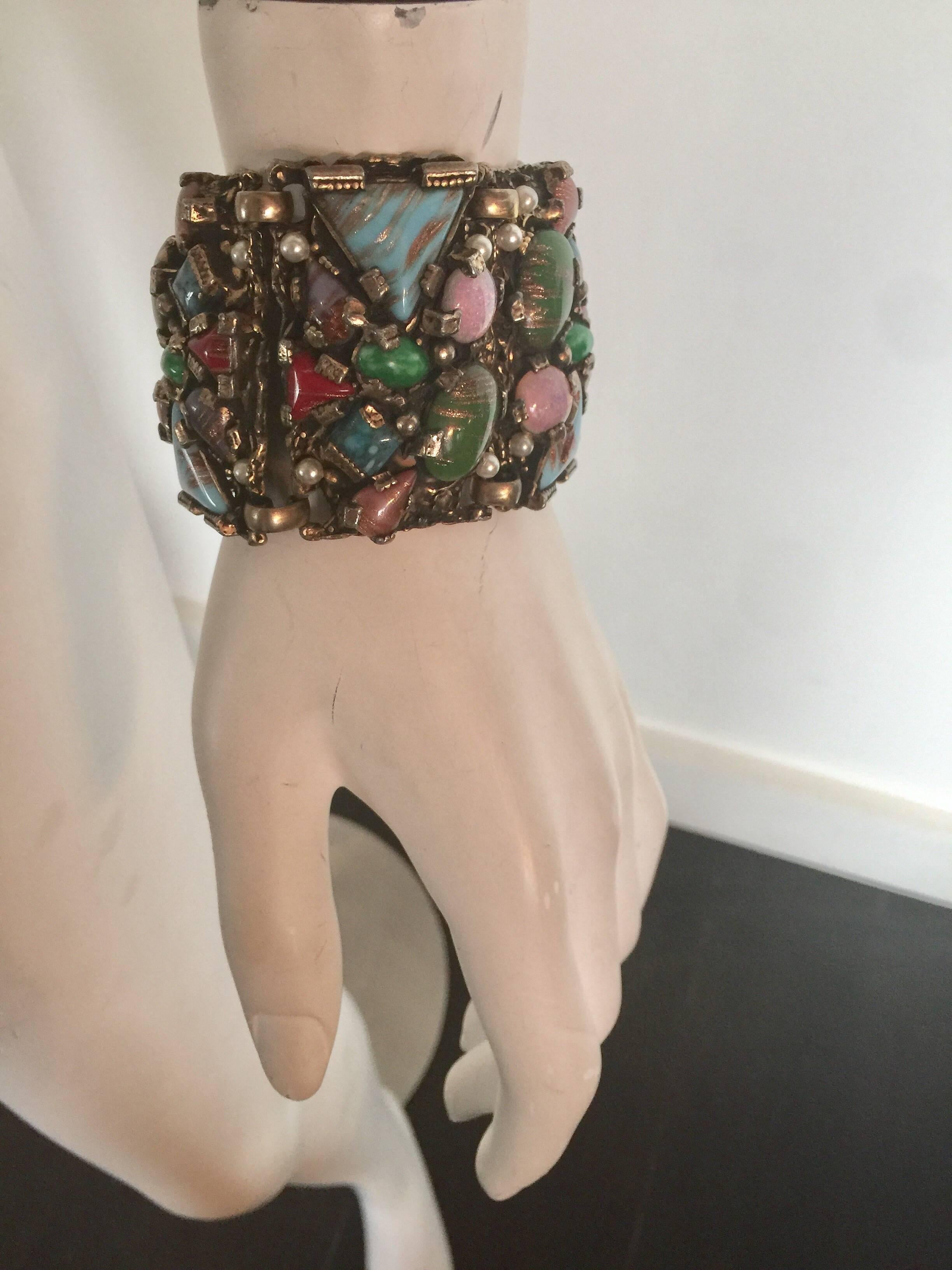 This large, chunky silver-tone bracelet looks like it may have once been gold plated.  The colored stones have a metallic element to them and faux pearls.  