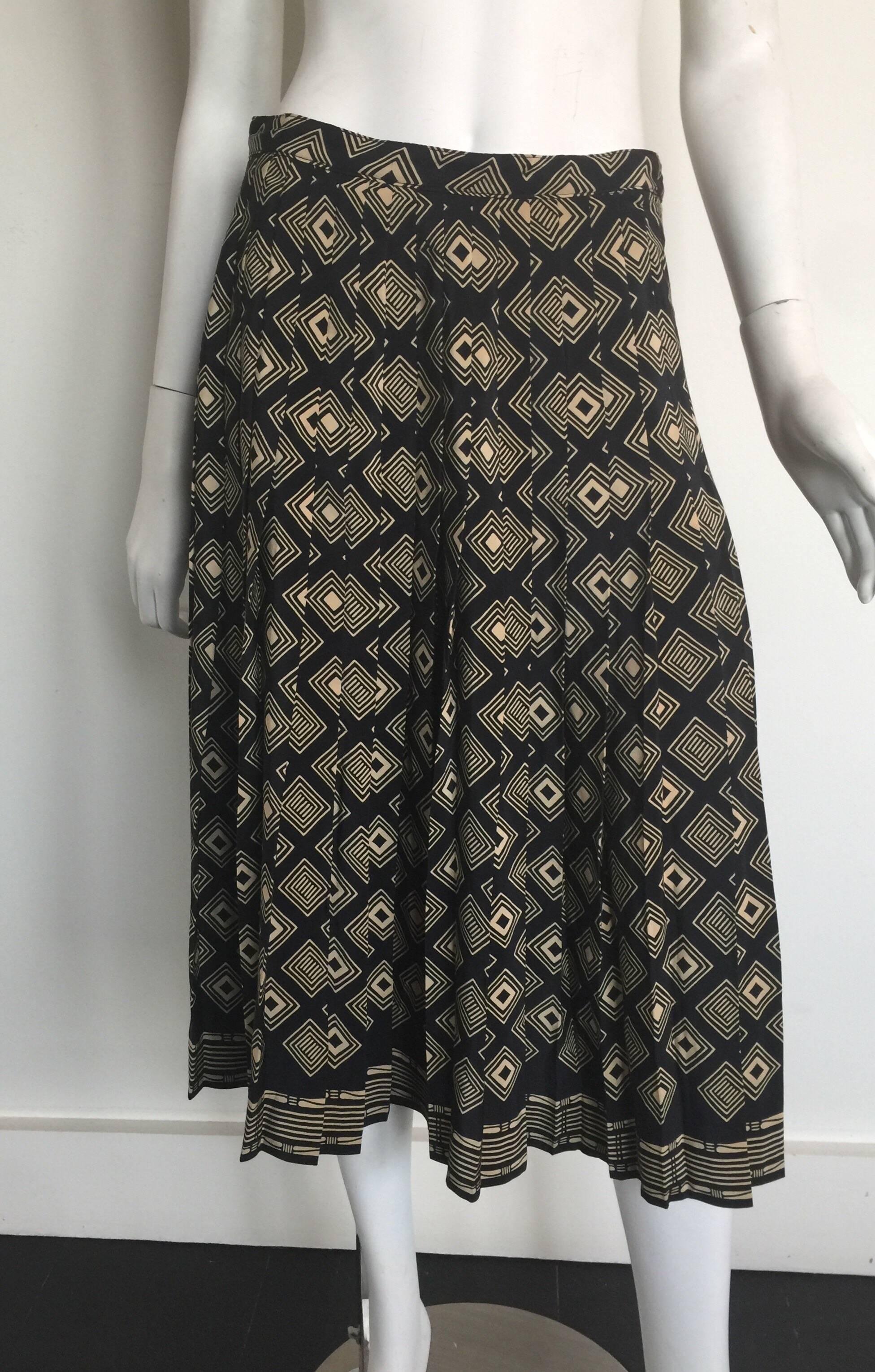 This Adolfo at Saks Fifth Avenue skirt is silk and pleated with a black and tan geometric print pattern.  It is high waisted and falls below the knee.  The skirt has a side button closure