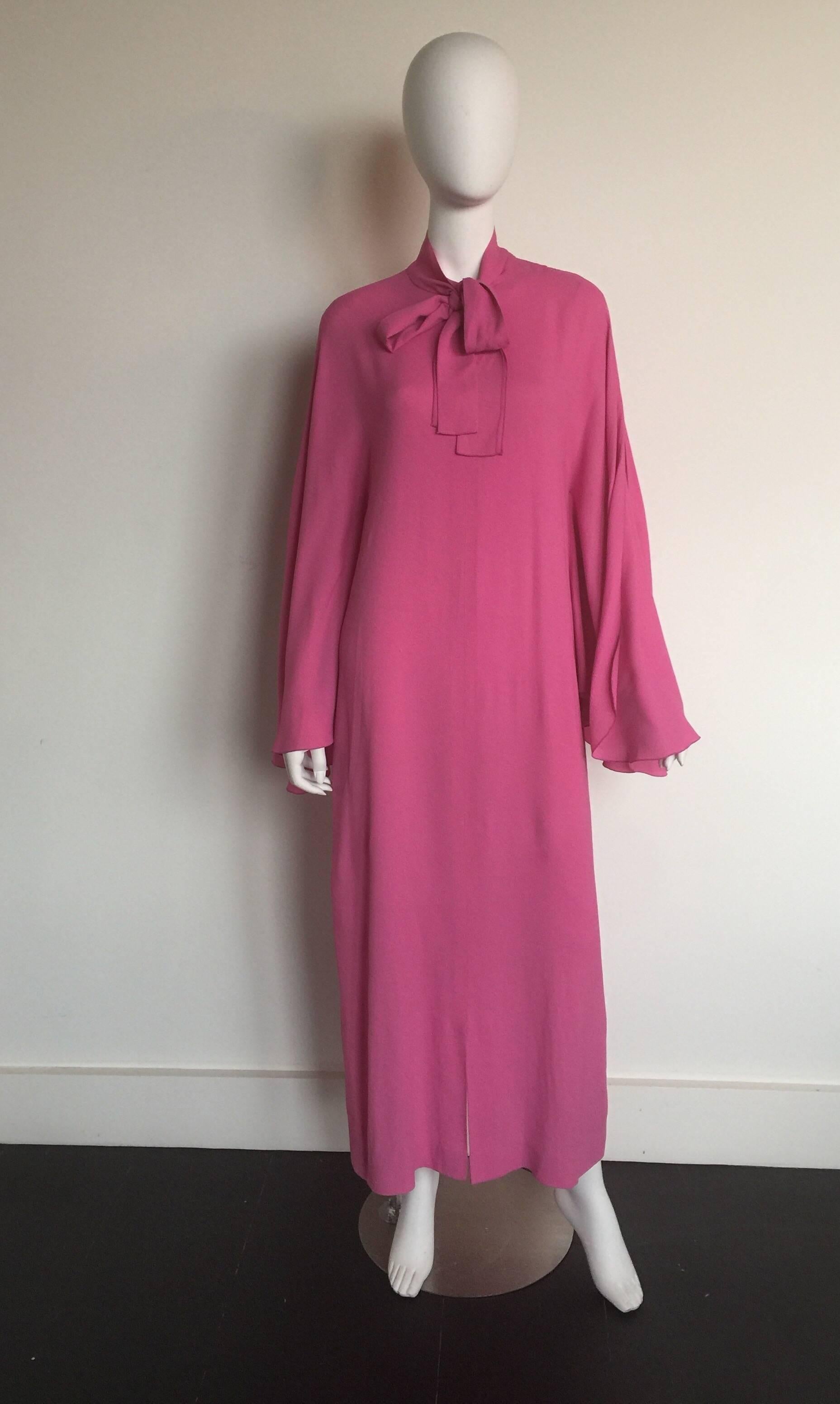 This Pierre Cardin caftan is from the 1960s. This pink caftan has a high neck with oversized bow. The flutter sleeves have a scalloped hem. There is a small front slit and a back zipper enclosure.

BUST: 40" 
WAIST: FREE WAIST 
HIP: FREE HIP