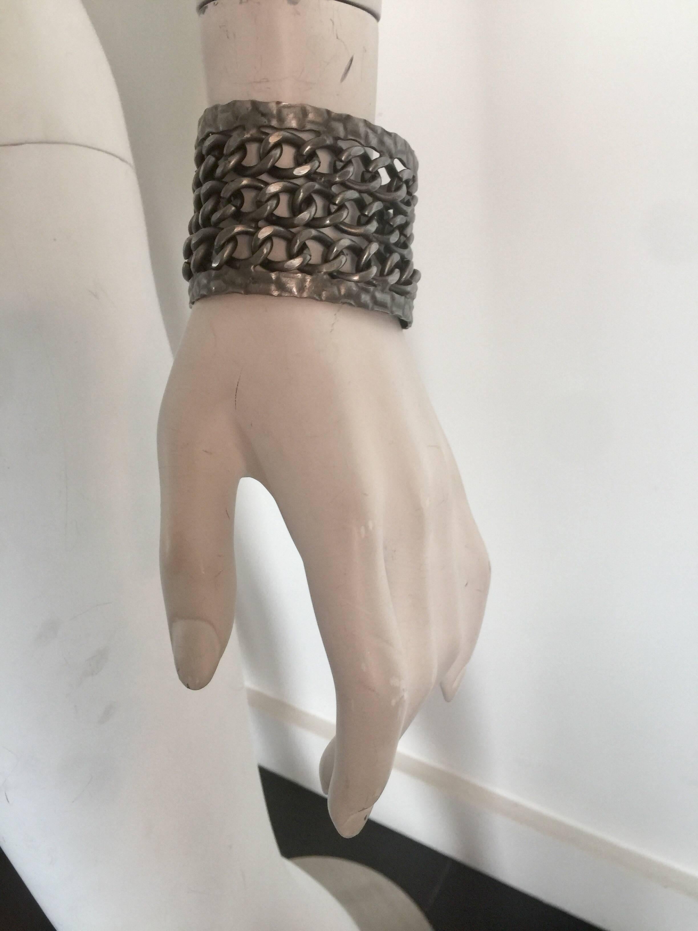 This blackened silver metal tone cuff has three rows of chains.  It is 2 inches wide and 7 long but is fairly adjustable and easy to take on and off.  