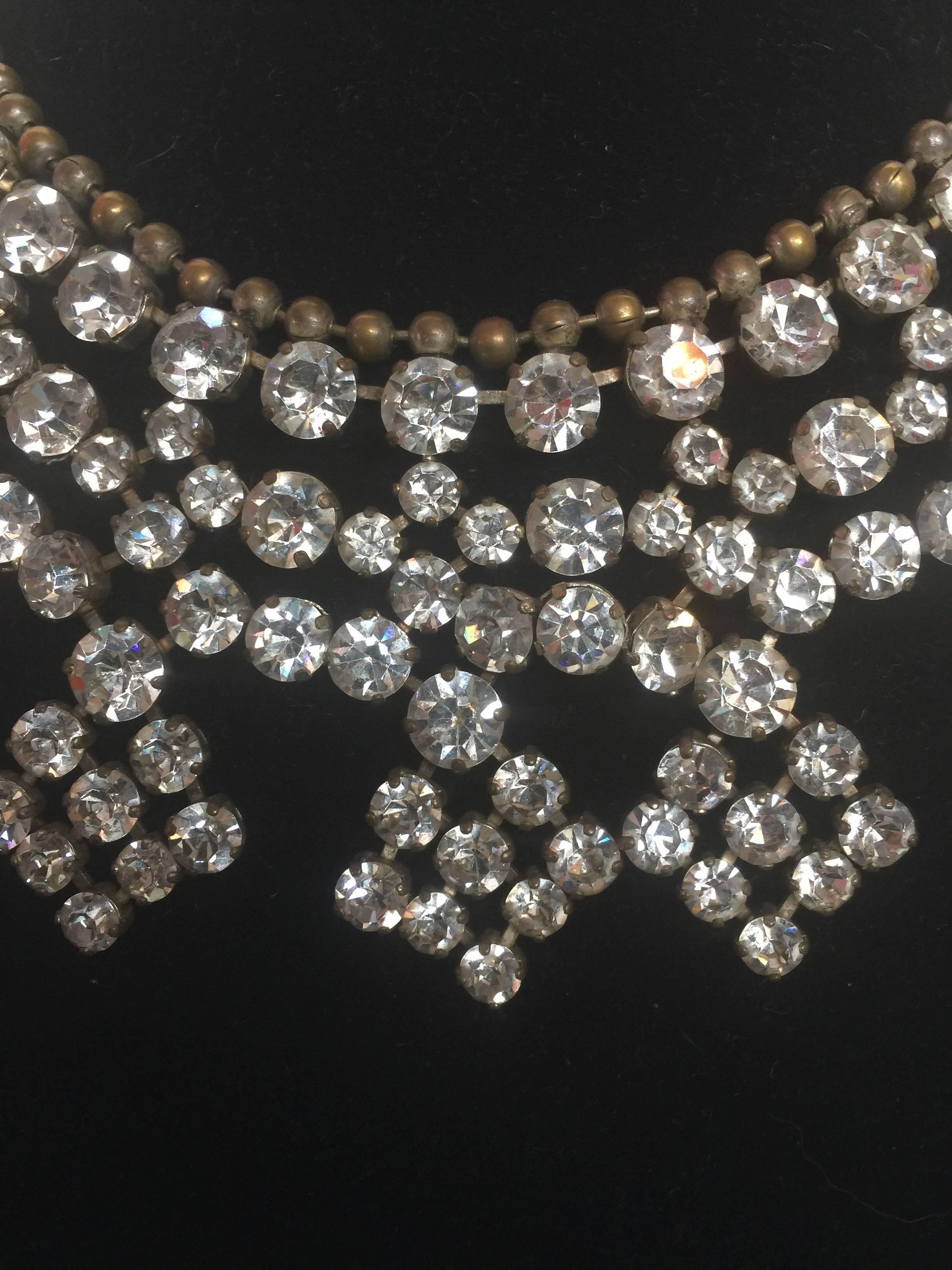 This large crystal bib necklace fits like the collar of a dress.  It can sit high around the neck and covers front and back.  It is in good condition and no crystals are missing 