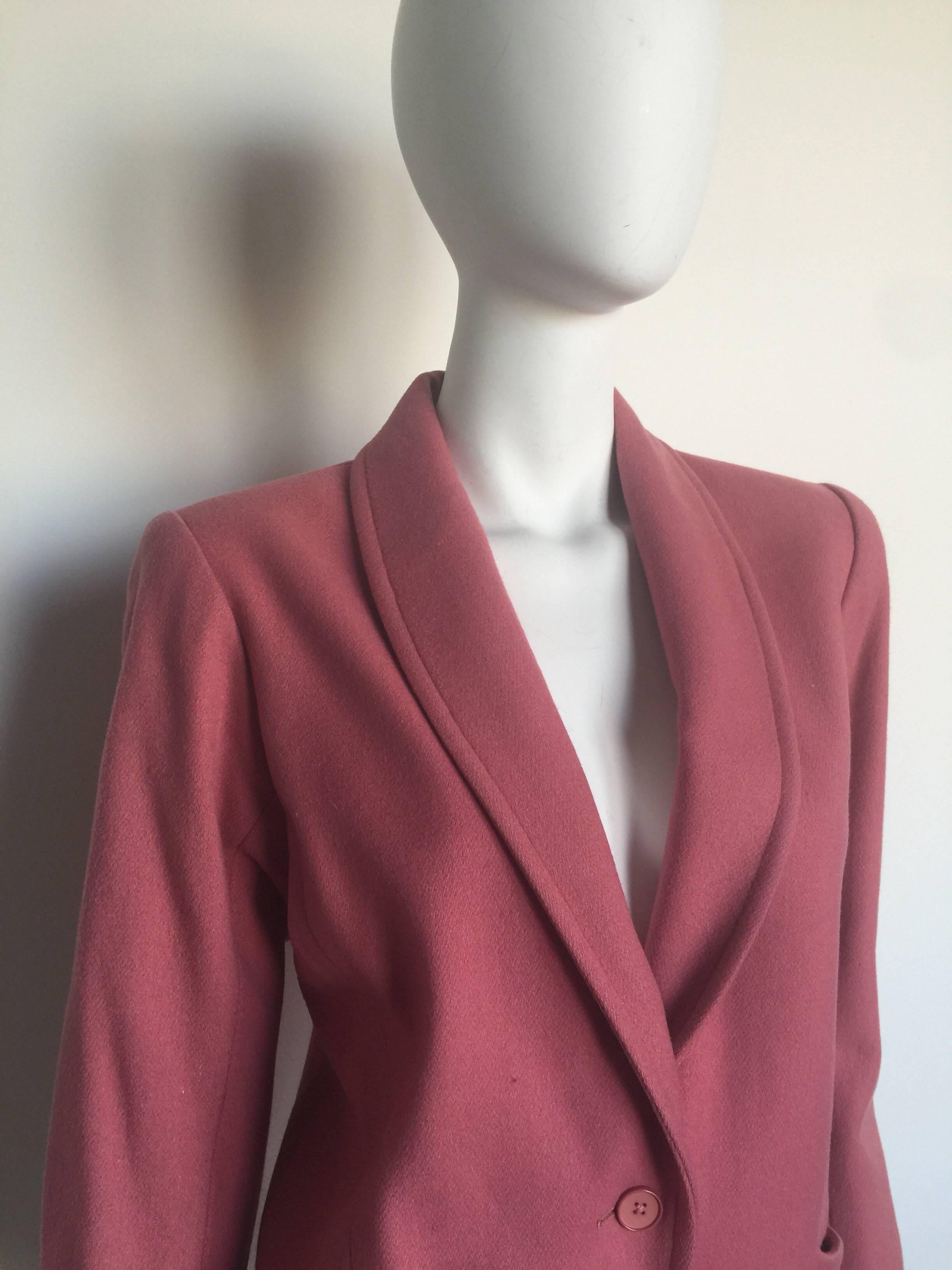 This single breasted blazer is a dusty pink wool blend blazer.  It is in good condition and listed as a size 34 but please refer to measurements and photos.  It has wrap side pockets and small shoulder pads. 