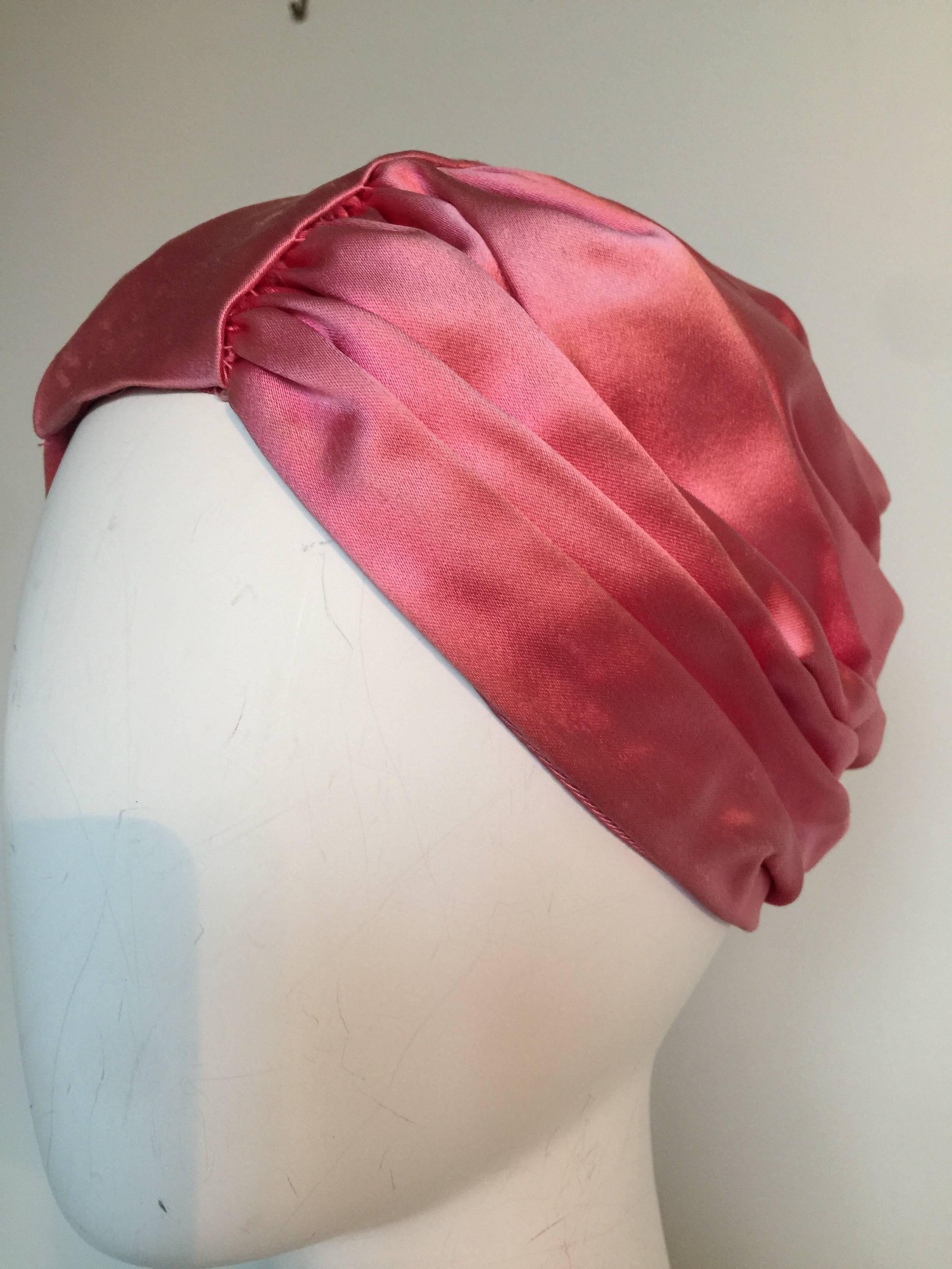 This pink silk turban is in fairy good condition with small pulls on the silk.  It is lined in pink as well. There is elastic in the back for a slightly adjustable fit. 