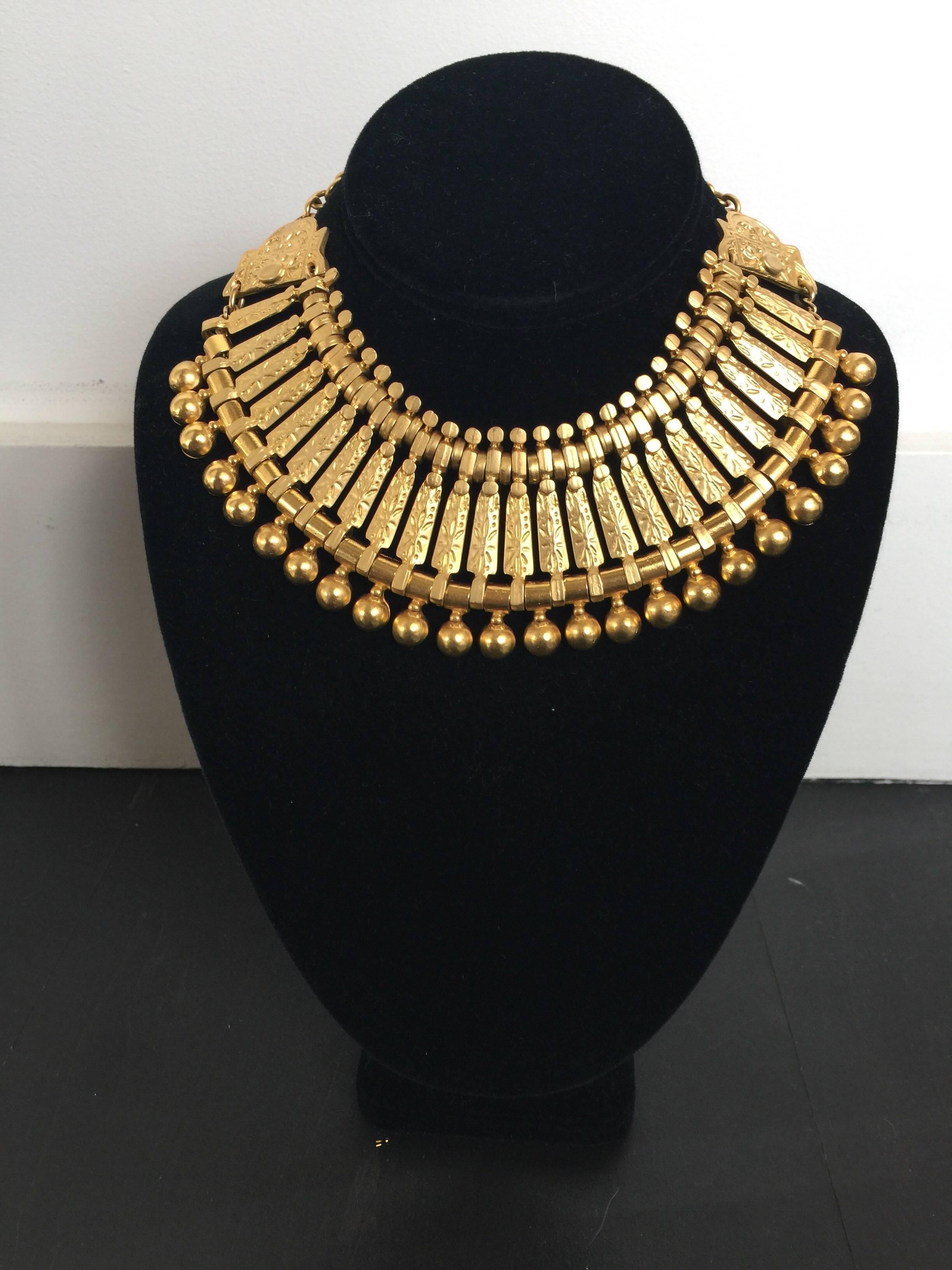This gold tone metal necklace has an Egyptian feel to it.  It has a moveable link bib and chain necklace with adjustable lengths. 