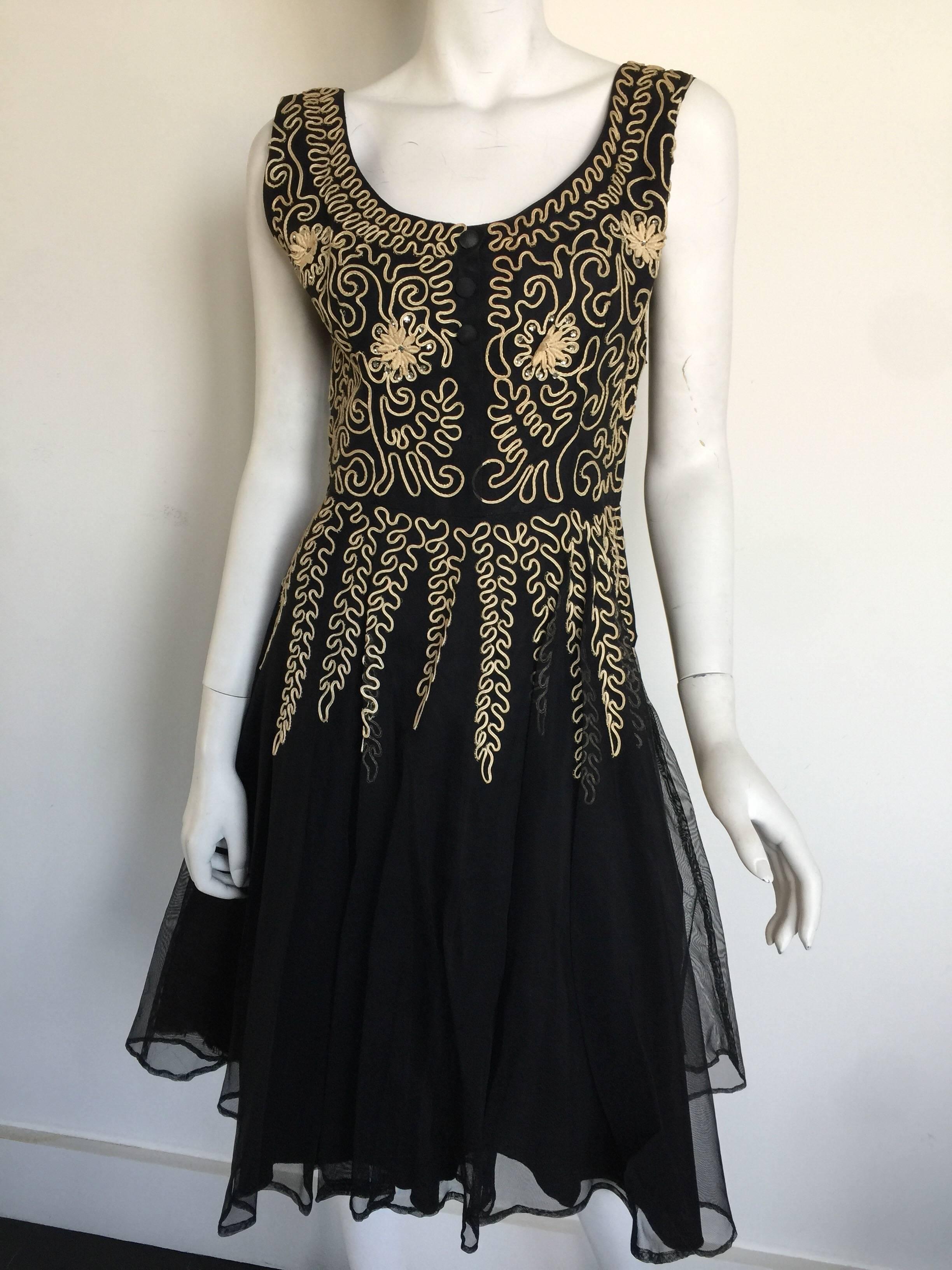 This black tulle dress has an off white ivory ribbon detail and crystal flowers.  The dress is from a NY Atelier and is most likely from the 1960s.  The dress is missing two of the original buttons and has slight discoloration but is still a special