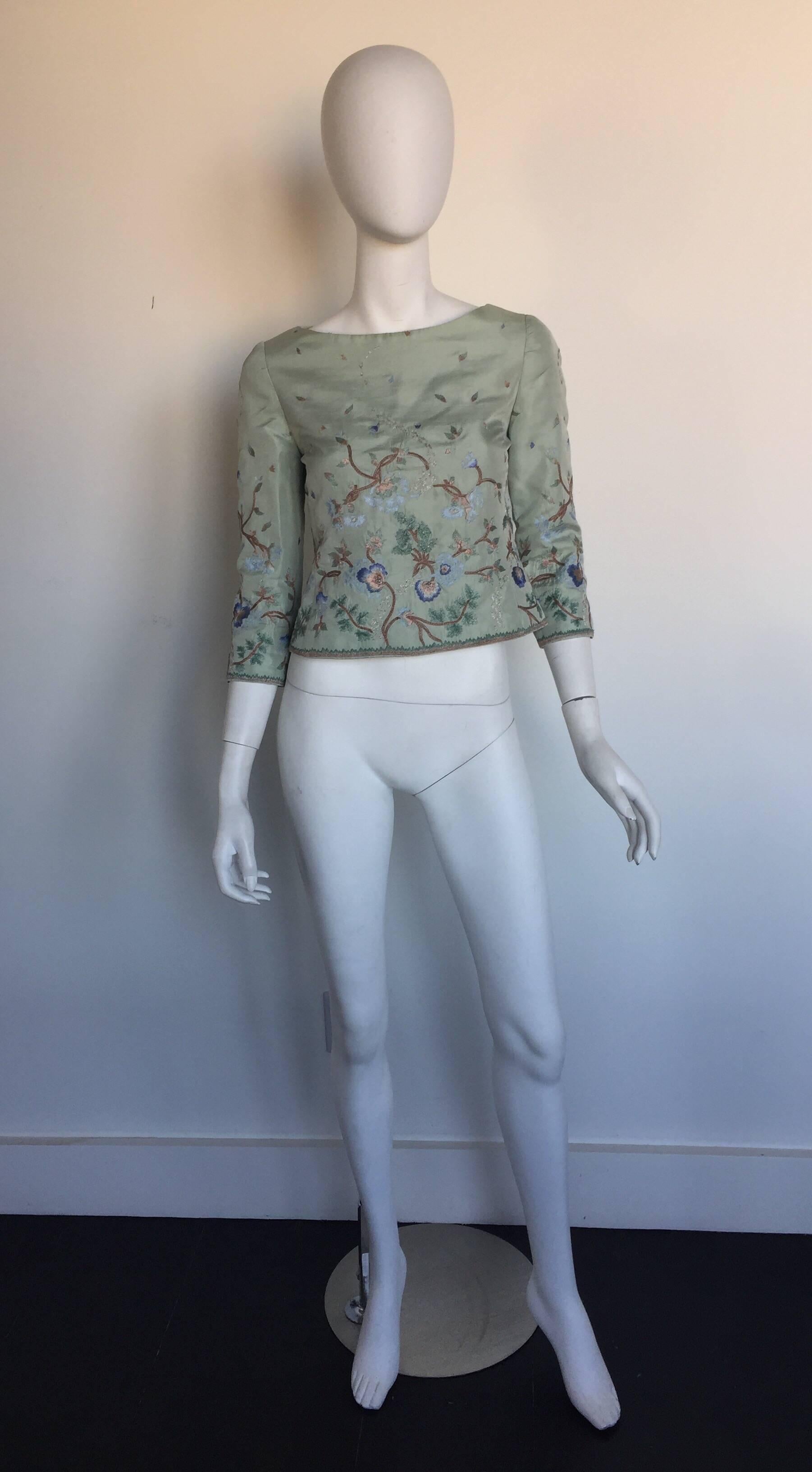 This Oscar de la Renta blouse is most likely from the 1990s.  It is a robins egg blue silk blouse and has beautiful bronze silver and blue embroidery.  It has a back zipper and skinny arms and a slightly boatneck blouse.  It is listed a size 6 but