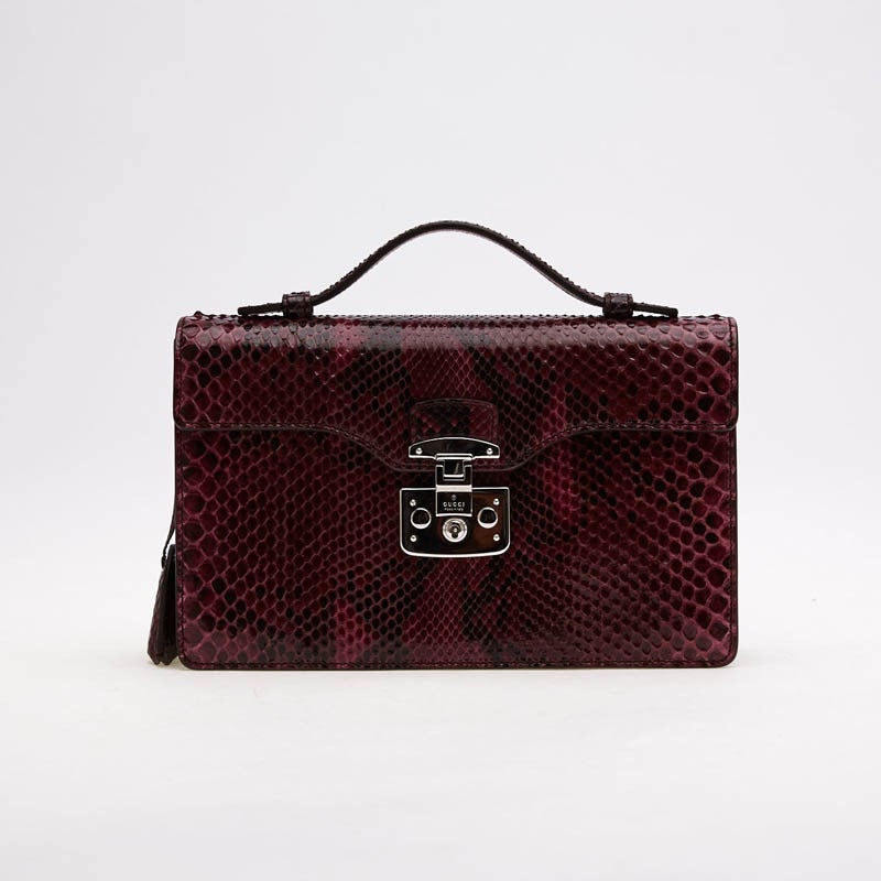 This petite Gucci Lady Lock Briefcase Clutch in Python is the perfect small accessory for the most stylish business person or a night out. This exotic wine-colored briefcase features a lock closure with keys. The flap has an interior zipped pocket