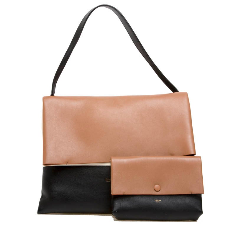 This beautiful Celine All Soft Tote is a desired handbag. It is constructed in tricolor calfskin leather in black, tan and white. This minimalist fold-over flap tote is light-weight and spacious and features a single leather strap. The matching