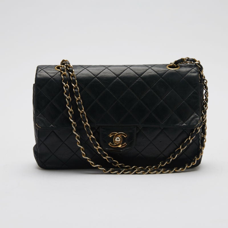 This authentic Chanel Classic Flap Lambskin in Medium is designed with the signature Chanel diamond quilt pattern. It features a double flap that keeps the bag more structured. Please note that this bag has considerable wear and shows various signs