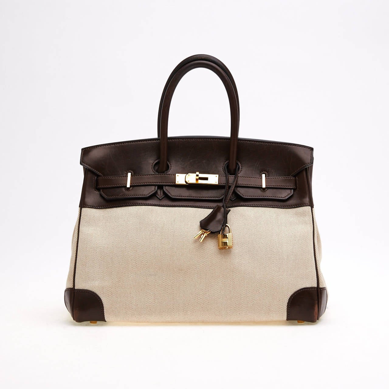 This authentic Hermes Birkin Leather and Toile in size 35cm is quite distinct yet understated. It is constructed with a Ebene chocolate brown leather trim and a Natural toile body. This contrasting design gives a new approach to the classic style