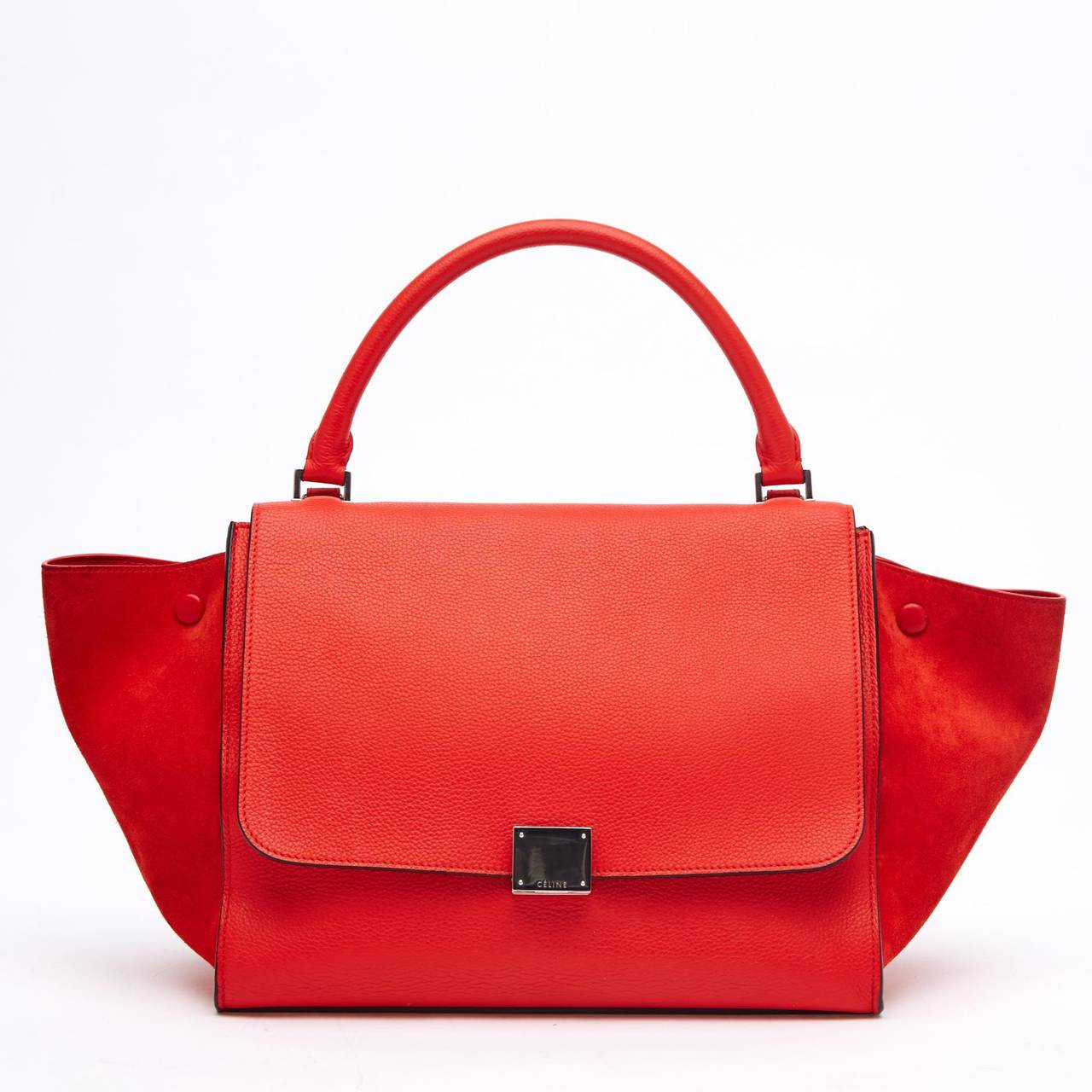 This authentic Celine Suede Trapeze in Medium is longed for by many, and it's no wonder why. This beautiful tote is constructed with blood orange leather and soft matching suede on the wings. It is accented with a silver opening buckle. Its soft