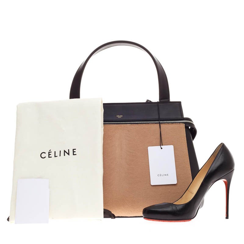 This authentic Celine Edge in size Medium is the quintessential Céline design mixing minimalism with luxury. The front face of the bag is crafted with fine tan pony hair and soft black leather. The bag features large silver zip-around hardware and