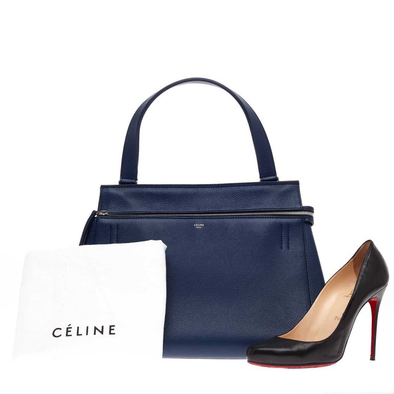 This authentic Celine Edge in size Medium is striking with its beautiful structure. The rich navy blue hue is contrasted with black zipper detail. The leather interior features two slip pockets and a zipped wall pocket. The base of the bag has four
