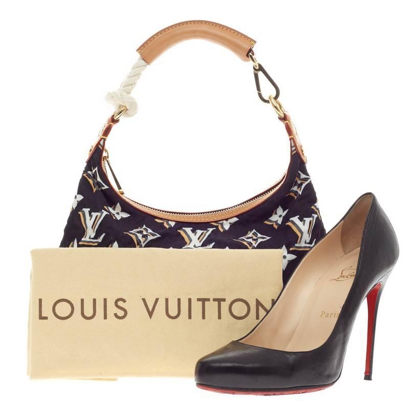 Questo autentico PM in nylon Bulles Monogram di Louis Vuitton, dal design chic e casual, è stato lanciato durante la Cruise Collection 2010 del marchio. Realizzata in nylon blu navy con stampa Monogram bianca, grigia e beige, questa borsa shoudler