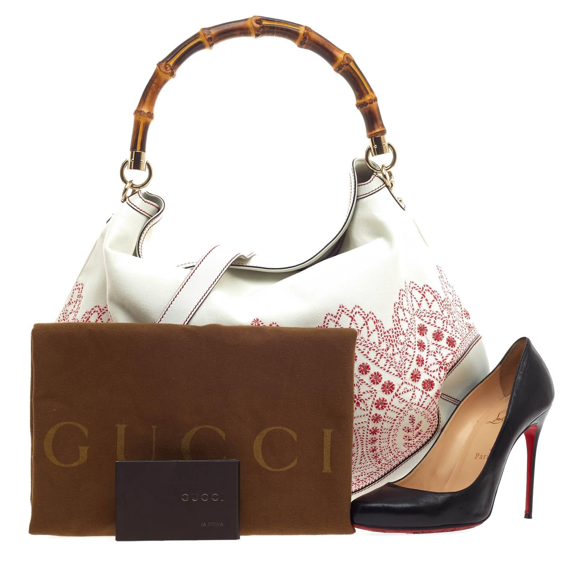 This authentic Gucci Peggy Bamboo Handle Hobo Embroidered Canvas is perfect for daily excursions. Crafted in white leather, this detailed hobo features an embroidered patterned canvas with red and white thread, signature bamboo top handle and