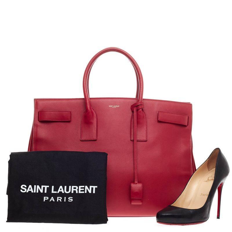 This authentic Saint Laurent Sac De Jour Leather Large is a sleek yet elegant bag synonymous with the brand's classic aesthetic. Crafted from vivid red calfskin leather, this oversized sought-out tote features a gold Saint Laurent embossed signature