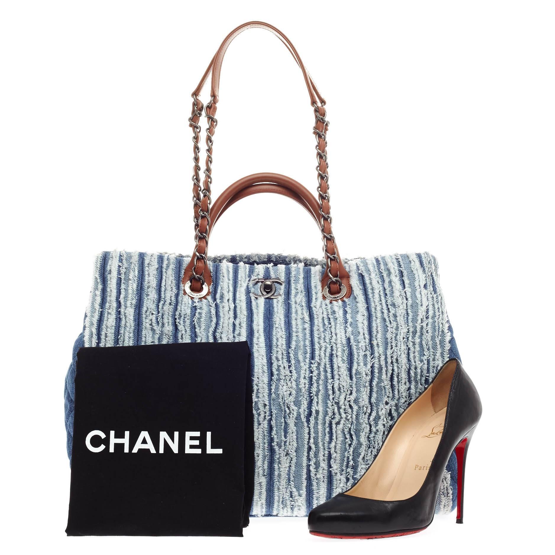 This authentic Chanel Shopping Tote Fringe Denim Large from the brand's Pre-Spring/Summer 2015 collection held in Dubai updated its classic tote design with meticulous design in a retro-inspired theme. Crafted in washed frayed denim, this stand-out