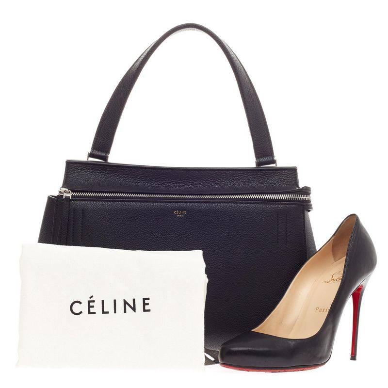 This authentic Celine Edge Bag Leather Small is the quintessential Céline design mixing minimalism with luxury. The bag is crafted with luxurious, classic black grained leather featuring a large silver zip-around closure and back pocket compartment