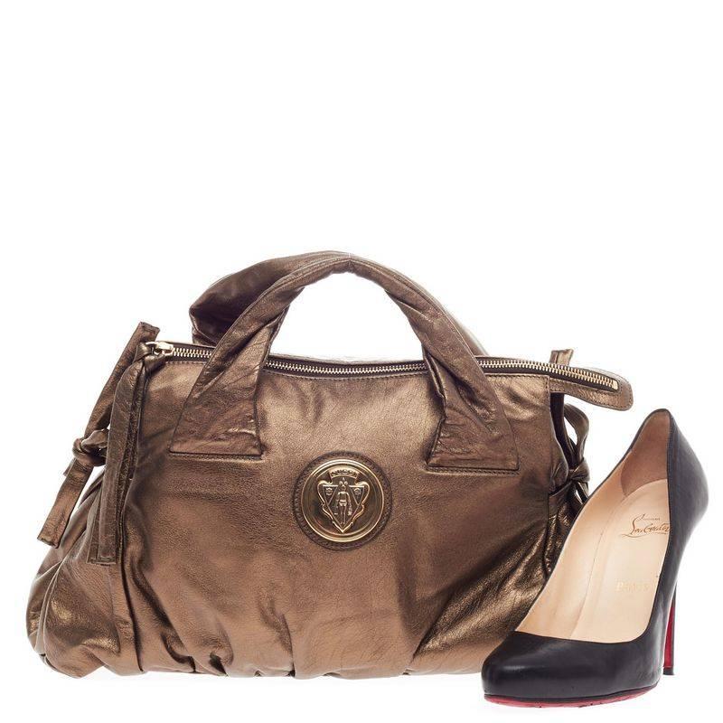 This authentic Gucci Hysteria Tote Leather Medium is a lovely addition for any Gucci lover. Constructed from metallic gold leather with olive undertones, this tote features bow ties on both sides for expansion, pleated details, Gucci crest, dual