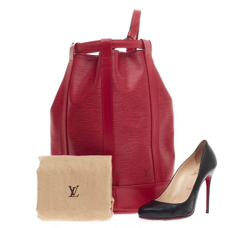 This authentic Louis Vuitton Randonnee Epi Leather PM in vivid rouge red shade combines the functionality of an everyday carry-all and classic style all in one. The unique backpack opens to a spacious red microfiber-lined interior  that closes with