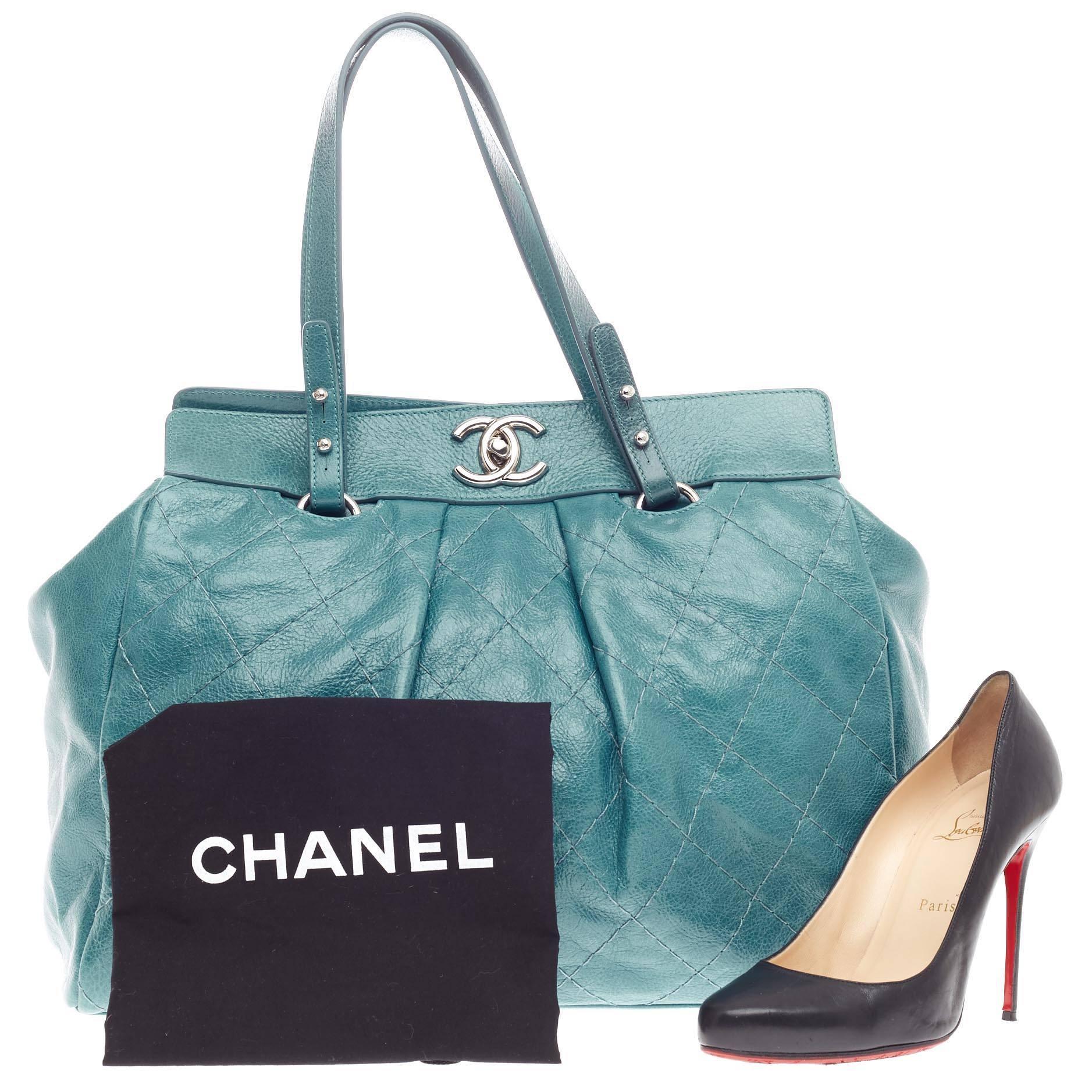 This authentic Chanel On the Road Frame Tote Glazed Leather showcases the brand's classic style with everyday functionality perfect for the modern woman. Crafted from deep teal glazed quilted leather with blue undertones, this tote features a soft