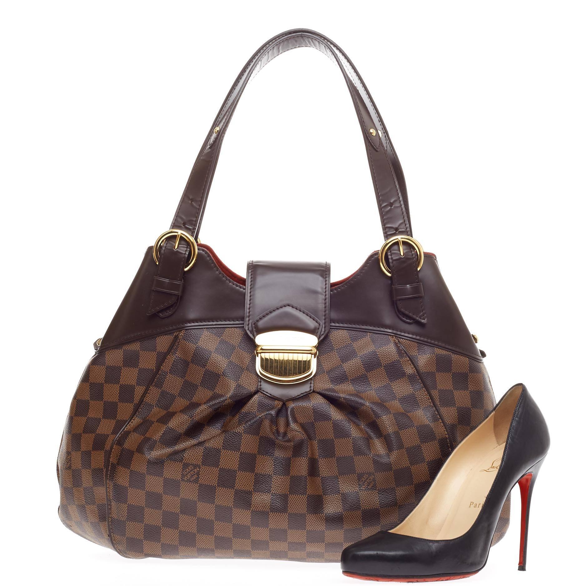 This authentic Louis Vuitton Sistina Damier GM is perfect for an everyday look for the modern woman. Crafted in the brand's iconic damier ebene canvas, this stylish yet feminine tote features subtle center pleating, smooth brown leather trims,