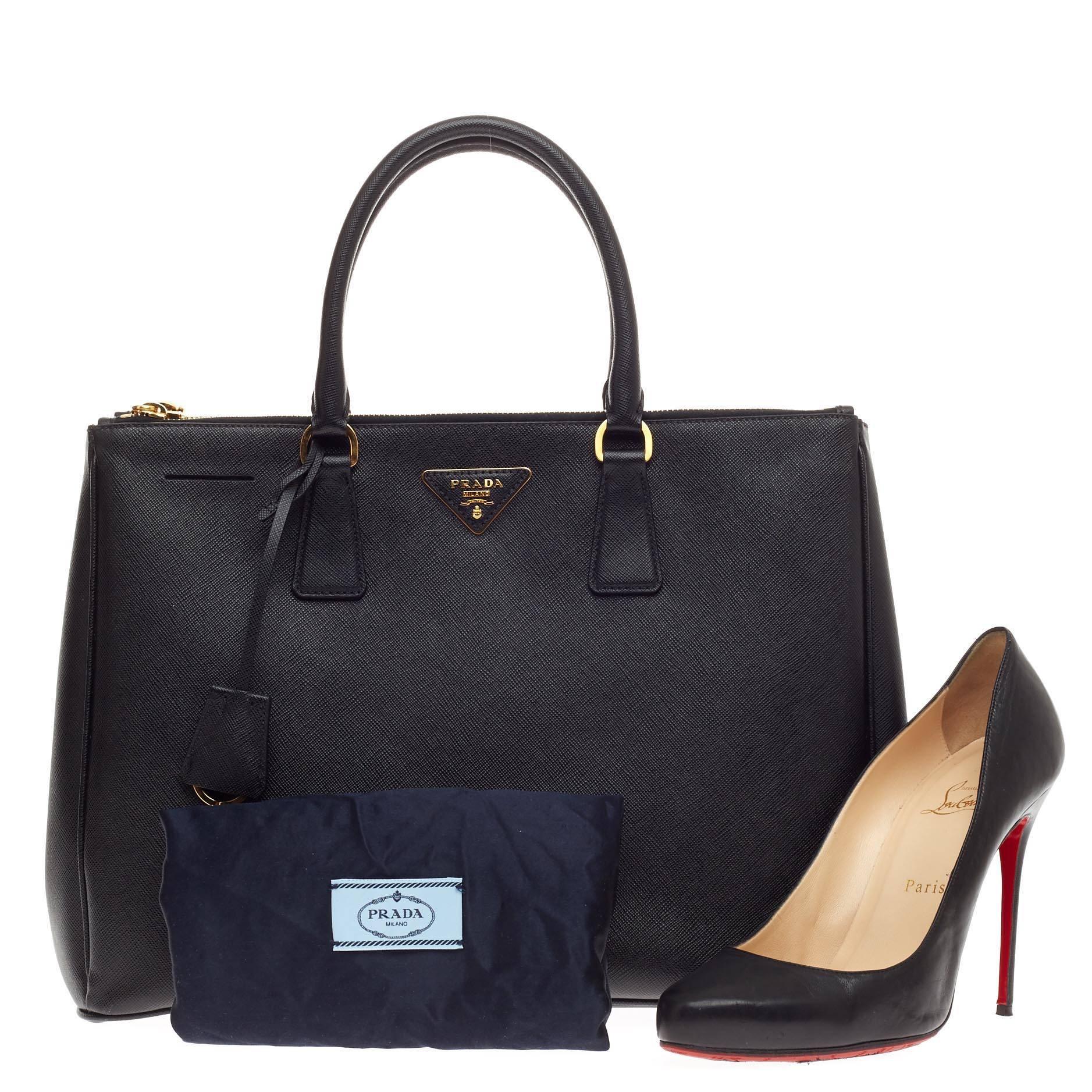 This authentic Prada Double Zip Lux Tote Saffiano Leather Medium is elegant in its simplicity and structure. Crafted from sturdy cross-grained nero black saffiano leather, this tote features, dual-rolled handles, raised Prada logo, leather clochette