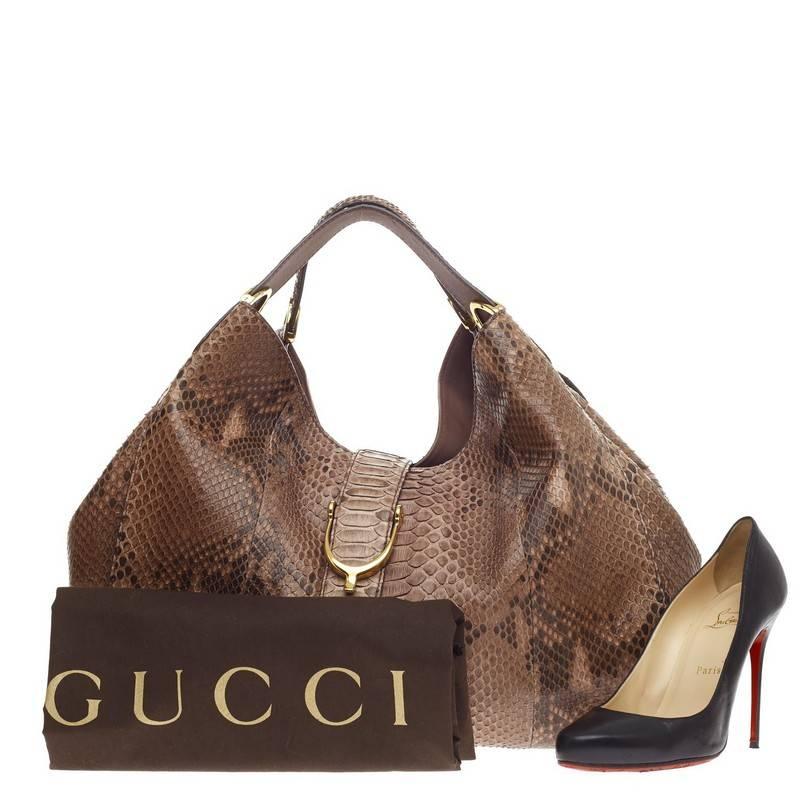 This authentic Gucci Soft Stirrup Tote Python Large in luxurious and sleek design is made for all seasons. Crafted from genuine brown python skin, this exotic hobo-style shoulder bag features side to side looped dual-flat handles with unique spur