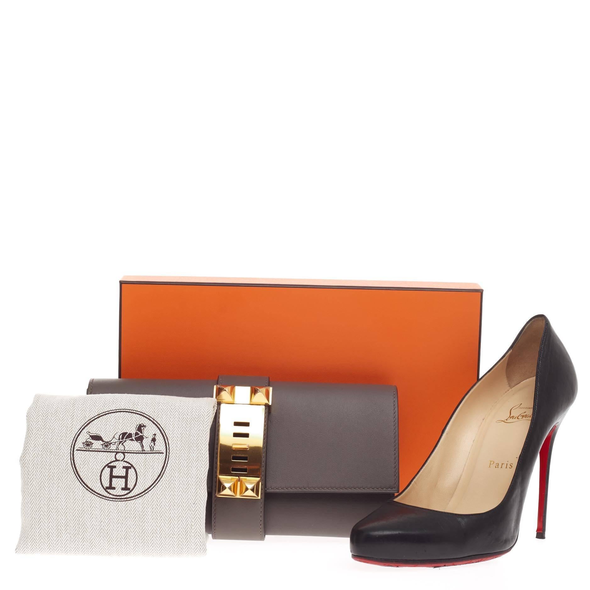 This authentic Hermes Medor Clutch Swift 23 is a hard-to-get, modern piece inspired by the brand's iconic 'collier de chien' hardware. Crafted from etain gray swift leather, this elegant clutch features a simple silhouette, with polished dog-collar