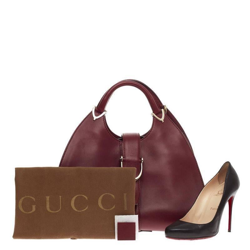 This authentic Gucci Stirrup Top Handle Bag Leather Large inspired by its 1975 iconic design is an elegant design with trademark equestrian flair. Crafted from dark red smooth leather, this structured top handle features dual-rolled handles with
