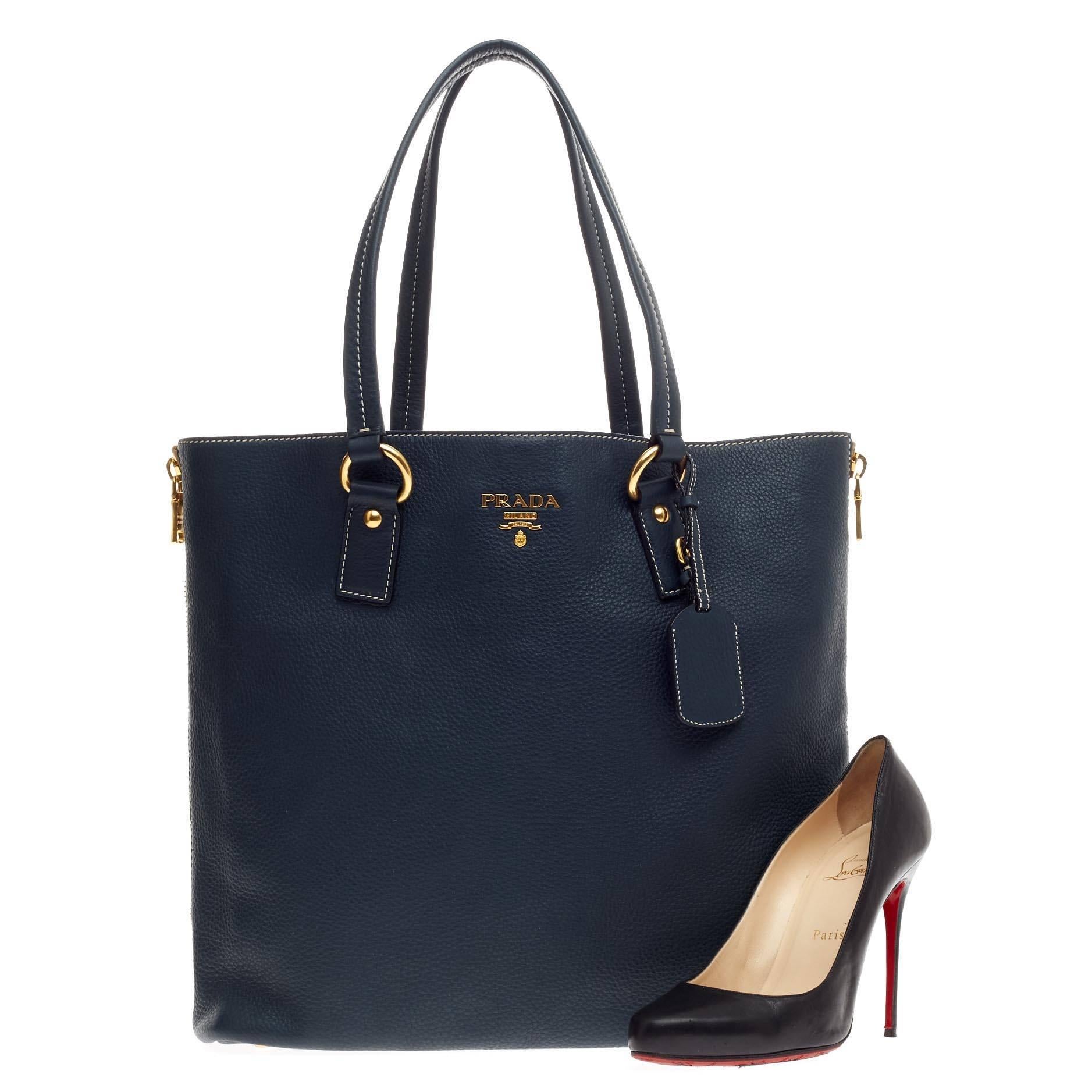 This authentic Prada Side Zip Convertible Shopper Tote Vitello Daino Large exudes a stylish and industrial design made for everyday excursions. Crafted from midnight blue vitello daino leather, this shopper tote features a sturdy base, dual tall
