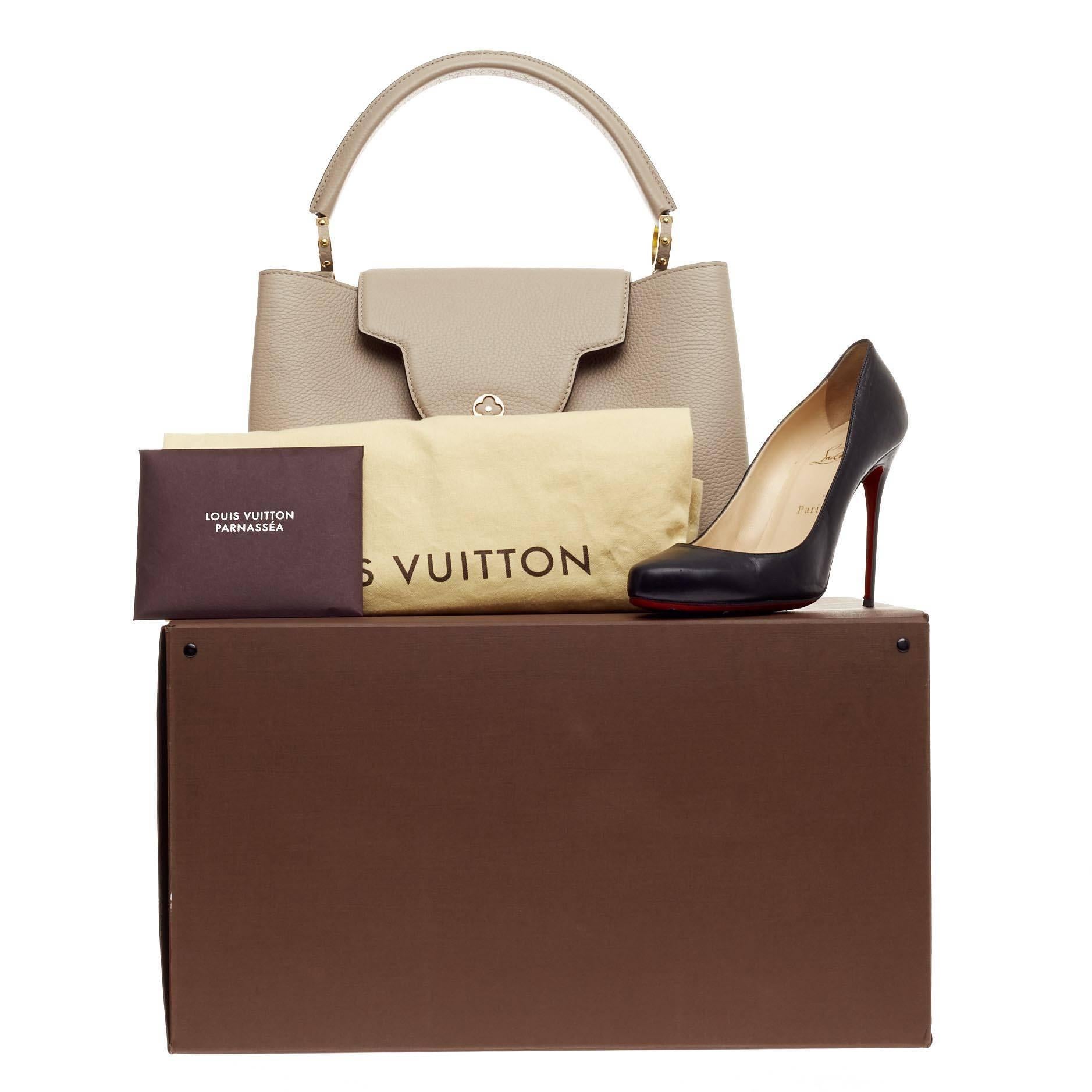 This authentic Louis Vuitton Capucines Leather MM is sophisticated and ladylike luxurious bag from the brand's Fall 2013 Collection inspired by its Parisian heritage. Crafted in galet beige taurillion leather, this chic, stand-out bag features a