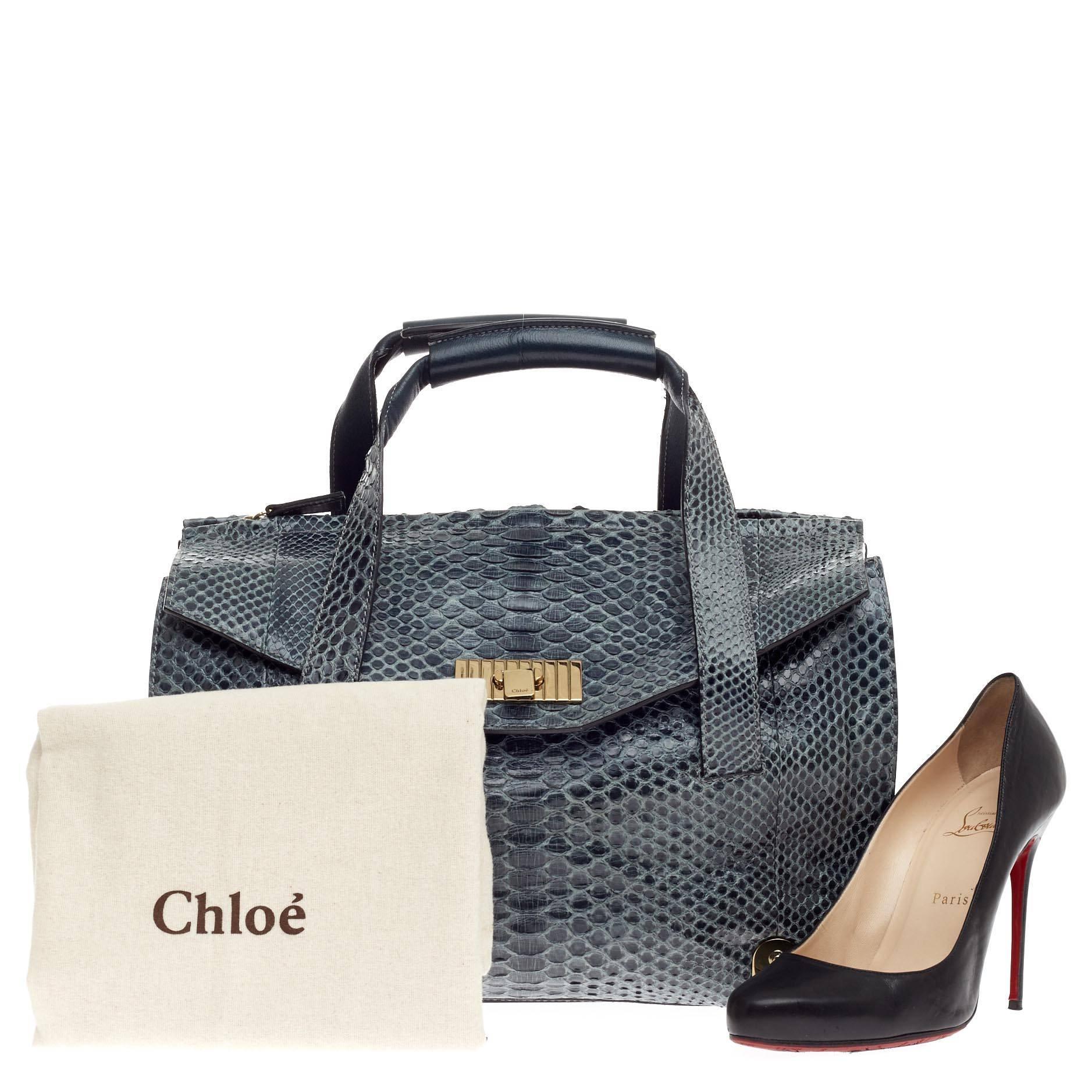 This authentic Chloe Sally Tote Python Large expresses casual elegance with exotic flair made for daily excursions. Crafted from dark blue genuine python skin, this tote features dual flat top handles with rolled pads, dark blue leather side panels,