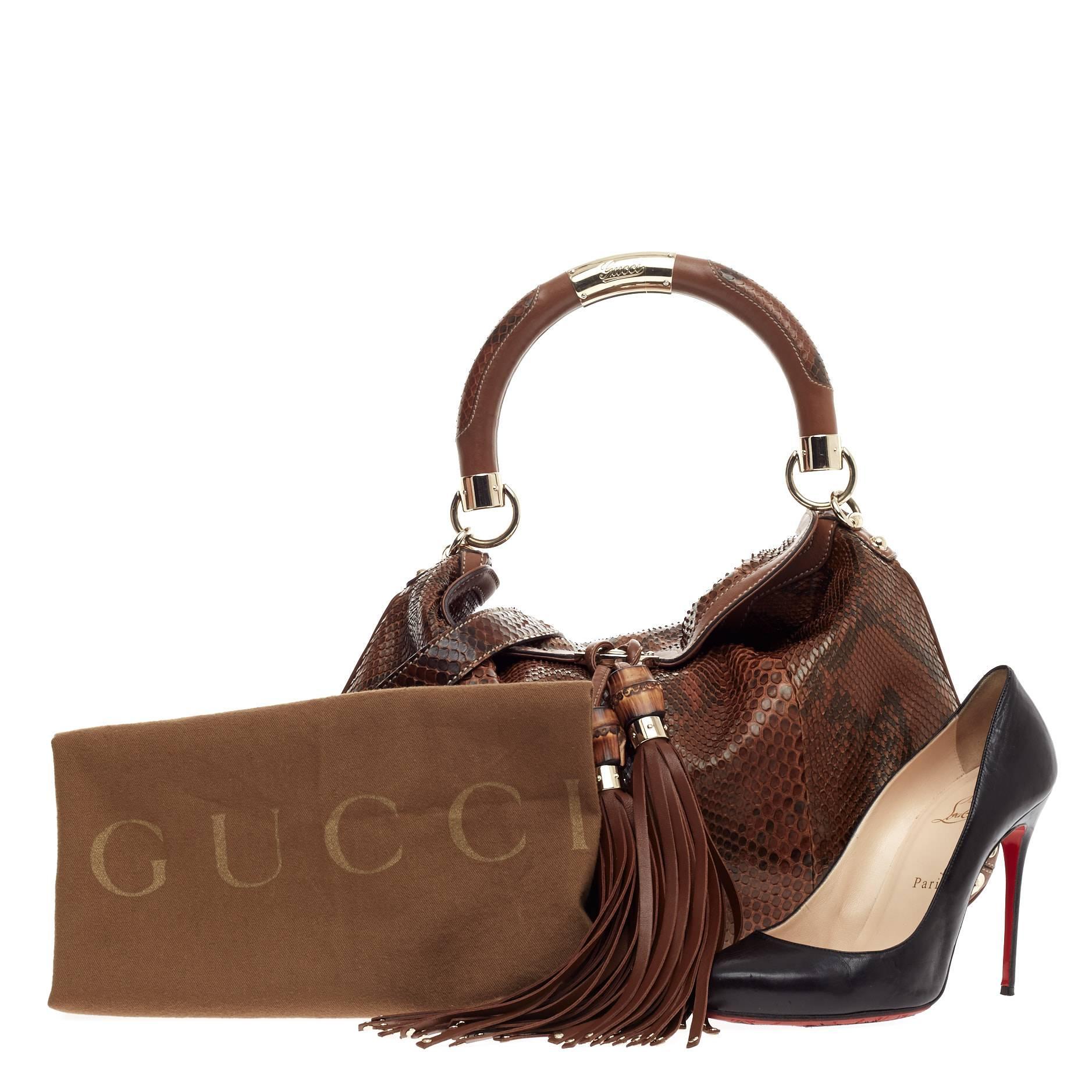 This authentic Gucci Indy Hobo Python Medium showcases the brand's classic design with luxurious detailing adding an exotic chic twist. Crafted from genuine dark brown python skin, this eye-catching hobo features bamboo and fringe tassels, chrome