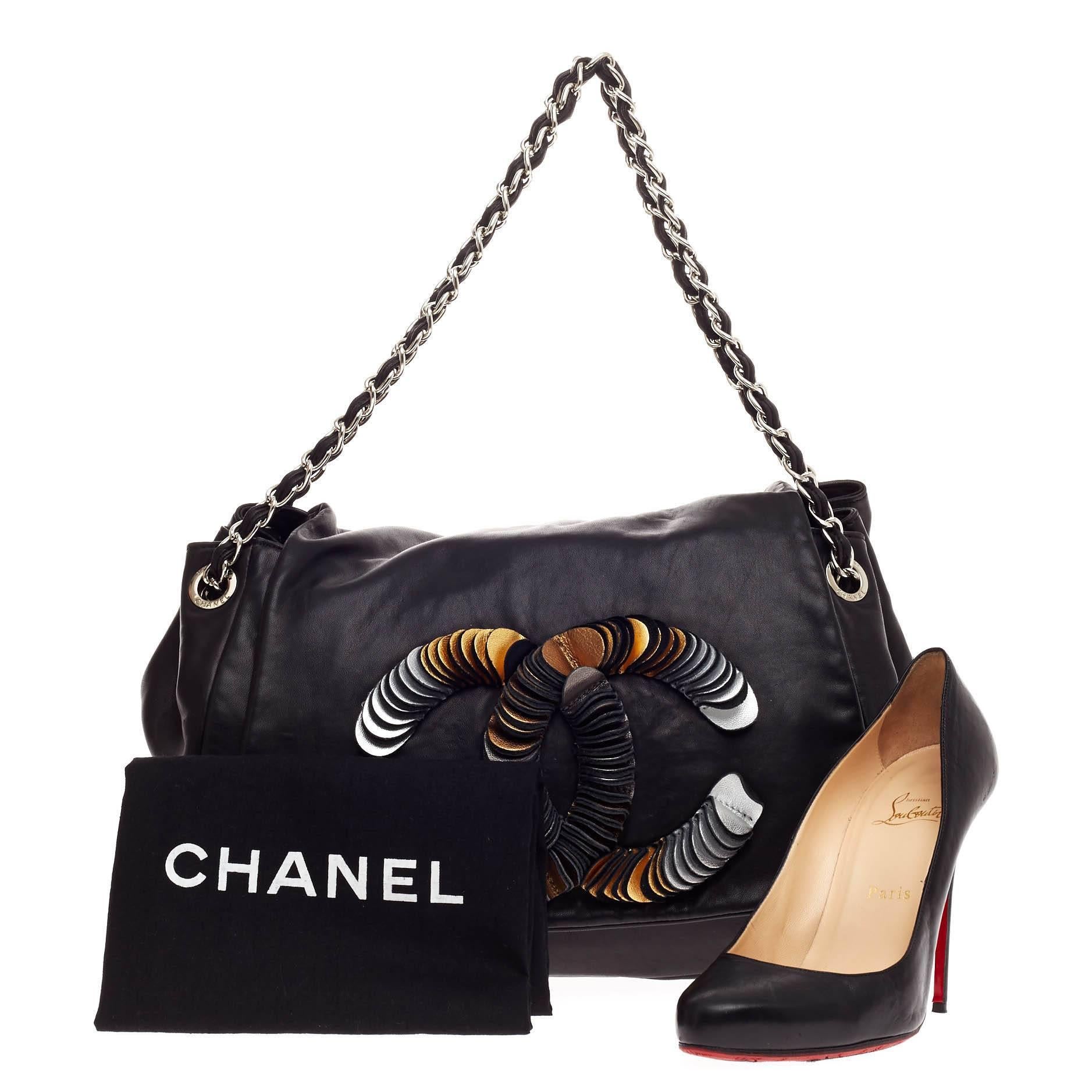 This authentic Chanel CC Disc Accordion Flap Lambskin presented in the brand's 2009 Collection showcases a modern and stylized design perfect for everyday use. Crafted from black lambskin leather, this limited edition flap bag features reversed