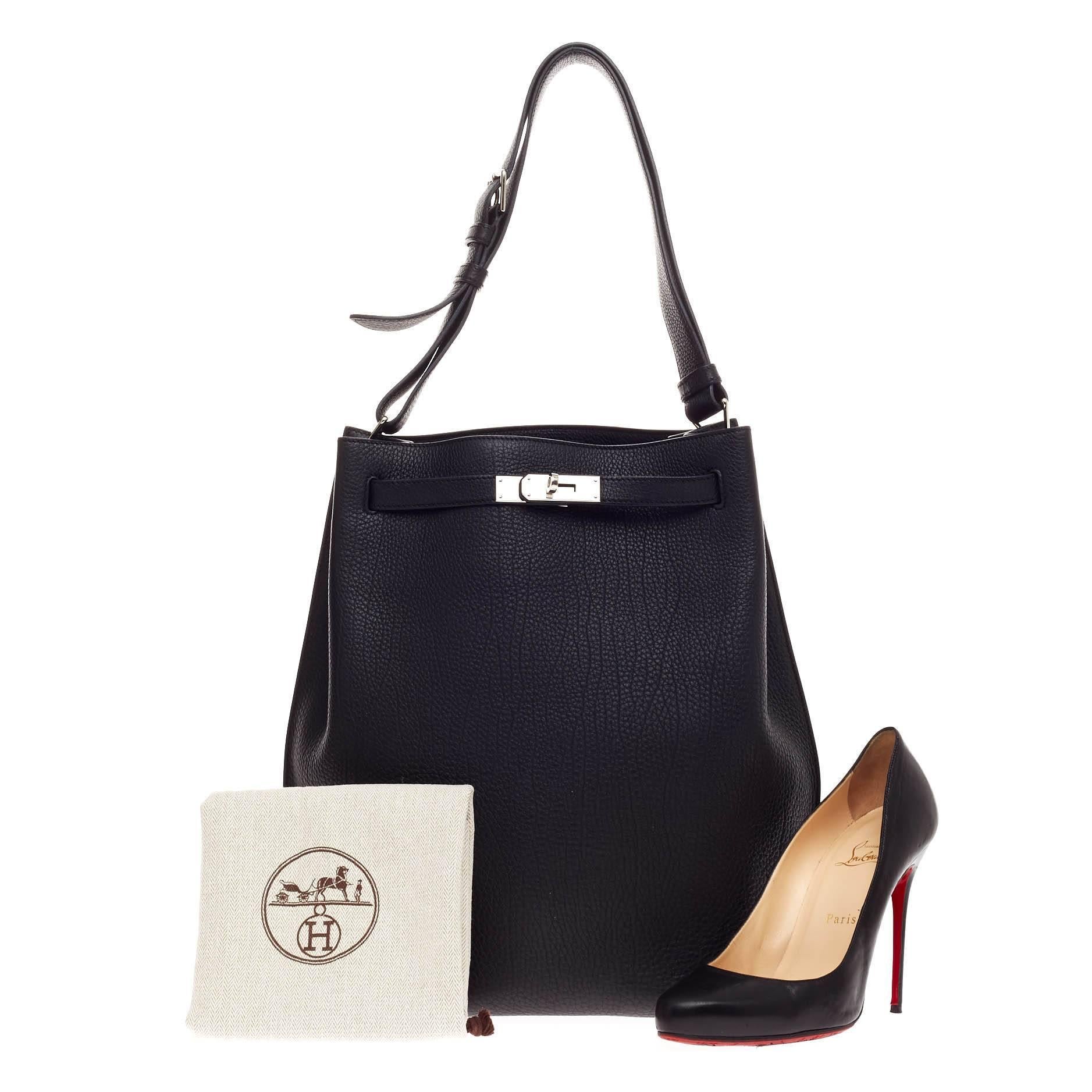 This authentic Hermes So Kelly Togo 26 first released in 2008 is an updated and modern reinterpretation of the Kelly Sport taking its distinct look to Hermes' classic kelly design. Crafted in black togo leather, this luxurious hobo-inspired bag