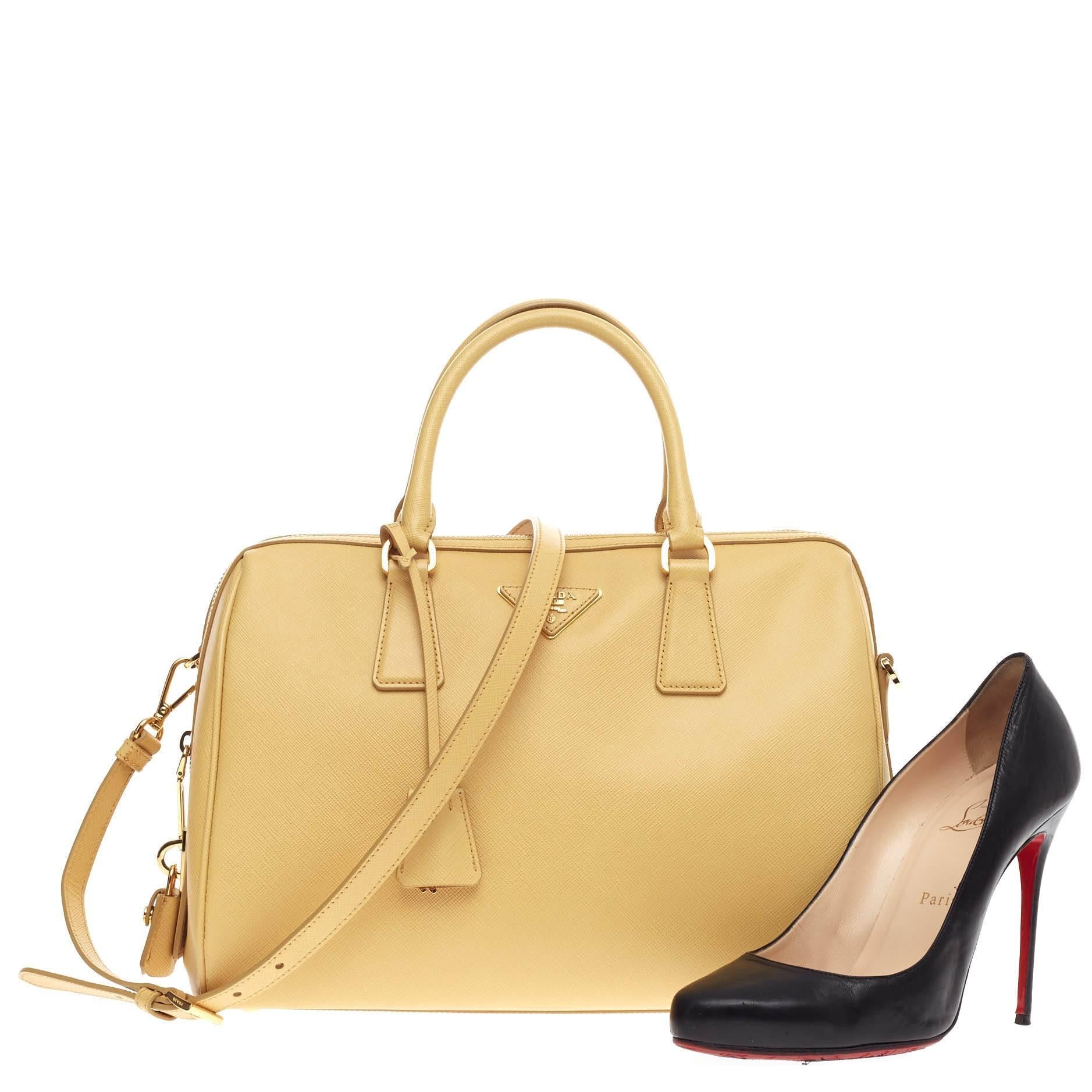 This authentic Prada Convertible Bowler Saffiano Leather Medium exudes a stylish and industrial design made for everyday excursions. Crafted from light yellow saffiano leather, this structured bowler satchel features dual-rolled top handles,