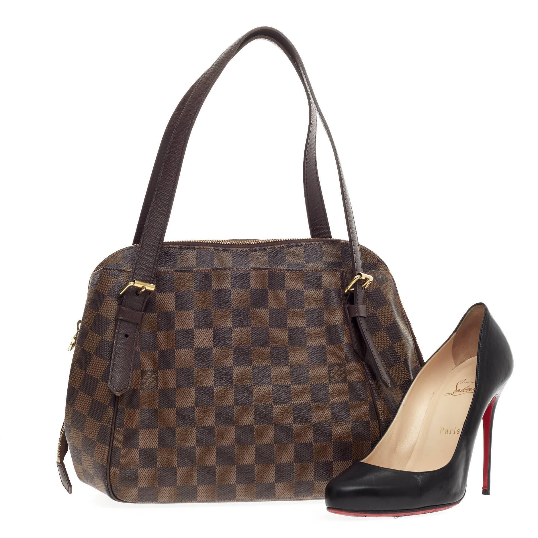 This authentic Louis Vuitton Belem Damier MM is a unique, functional everyday piece for any Louis Vuitton lover. Crafted from the brand's popular damier ebene canvas print, this tote features dual flat brown leather handles, brown leather piping,