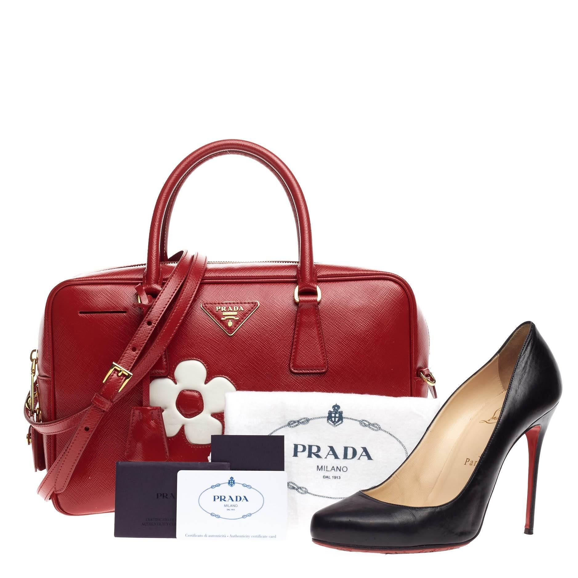 This authentic Prada Flowers Bauletto Vernice Saffiano Leather Medium exudes a stylish and industrial design made for everyday excursions. Crafted from rosso bianco red textured saffiano vernice patent leather and white smooth leather, this satchel