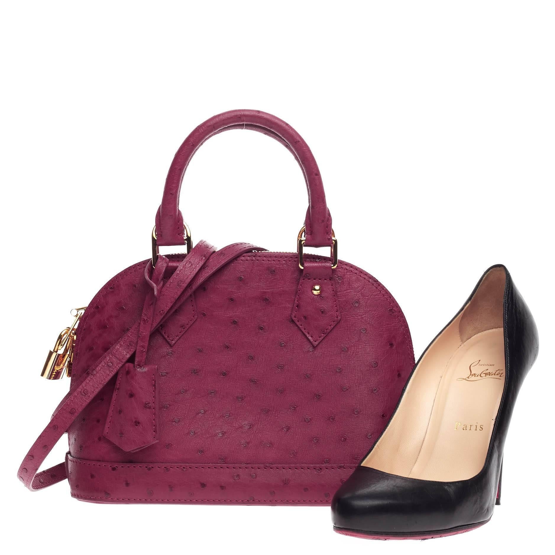 This authentic Louis Vuitton Alma Ostrich BB is a chic and sophisticated bag perfect for everyday use. Constructed in genuine fuchsia ostrich skin, this petite dome-like bag features a sturdy base, protective base studs, dual-rolled handles,