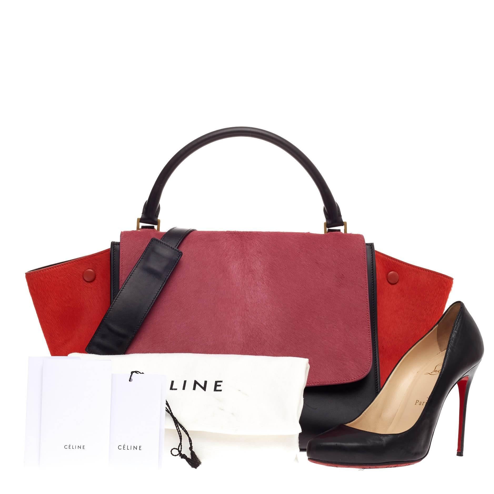 This authentic Celine Tricolor Trapeze Pony Hair Medium presented in the brand's 2014-2015 Collection is a modern minimalist design with a playful twist in an array of subdued colors. Crafted from pink and red pony hair and black leather, this