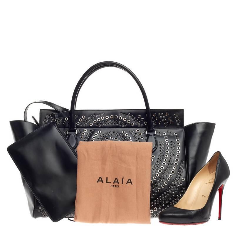 This authentic Alaia Grommet Zip Tote Leather Large personifies the brand's quintessential sleek yet chic everyday style. Designed in black leather, this oversized tote features, dual-rolled handles, beautiful geometric laser cut with gunmetal-tone