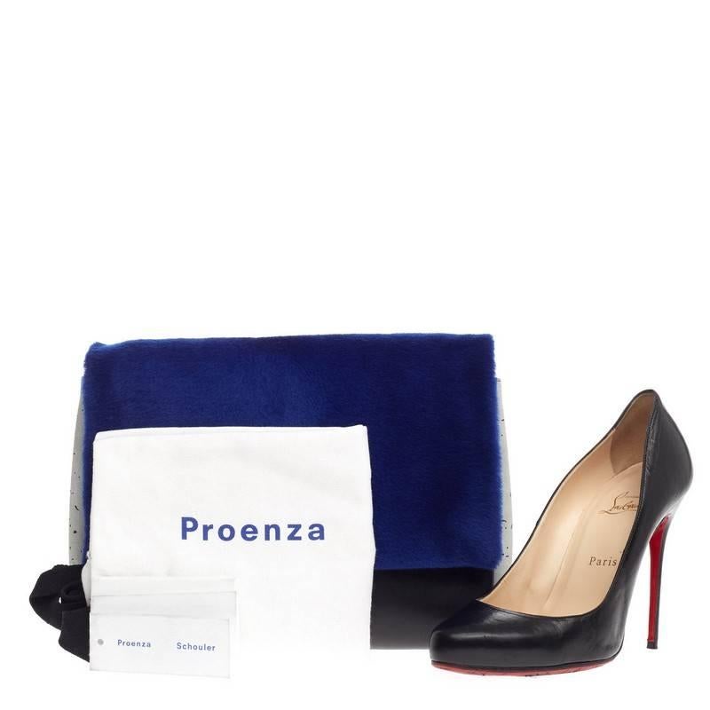 This authentic Proenza Schouler Elliot Clutch Calf Hair and Leather is modern and uniquely edgy in design. Crafted from plush electric blue calf hair and black leather, this clutch features light grey splatter-print suede sides, front flap with