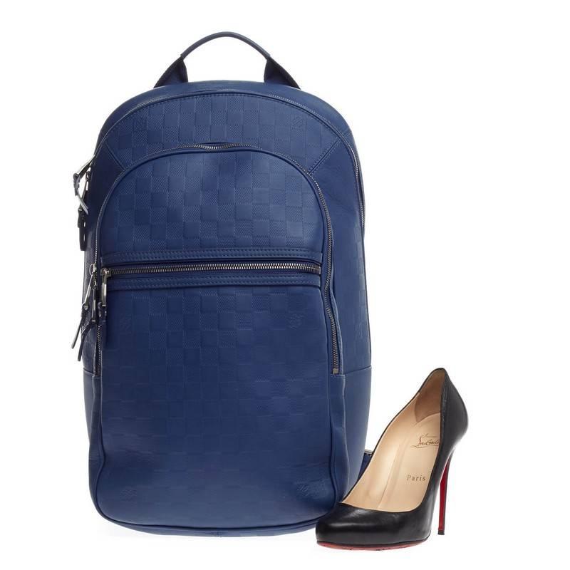 This authentic Louis Vuitton Michael NM Damier Infini Leather is a lightweight, luxe backpack combining style and comfort. Crafted from neptune blue damier infini leather, this chic, hands-free backpack features a short flat leather top handle, two