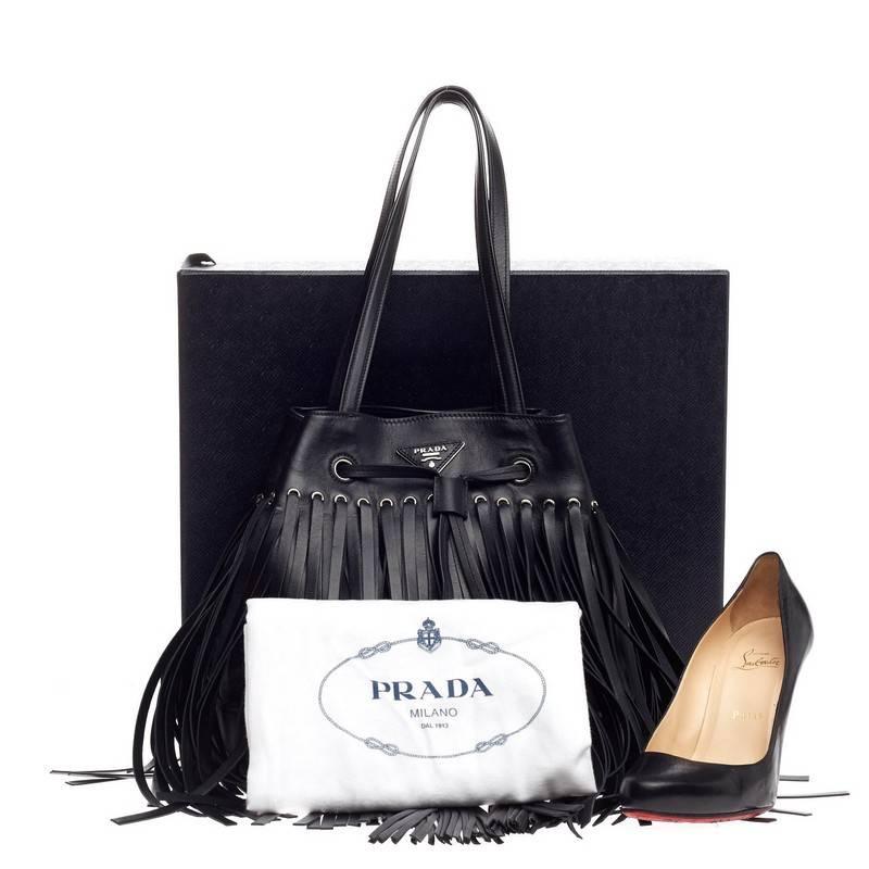 This authentic Prada Fringe Bucket Bag Soft Calfskin Large presented in the brand's 2014 Collection is sophisticated and modern in style perfect for everyday use. Crafted from black smooth leather, this bucket bag features leather fringe with