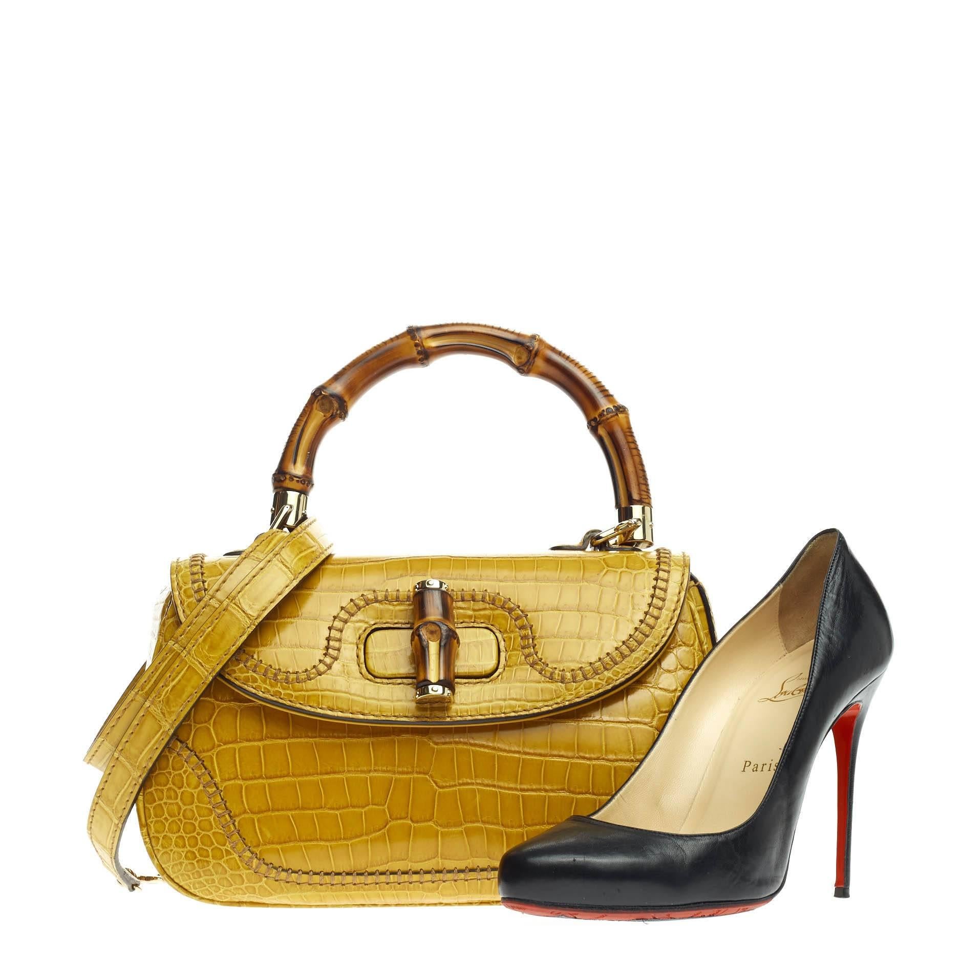 This authentic Gucci New Bamboo Convertible Top Handle Crocodile Medium is unmistakably a classic and timeless Gucci design made for avid fashionistas. Crafted in genuine mustard yellow crocodile skin, this re-imagined iconic bag features a bamboo