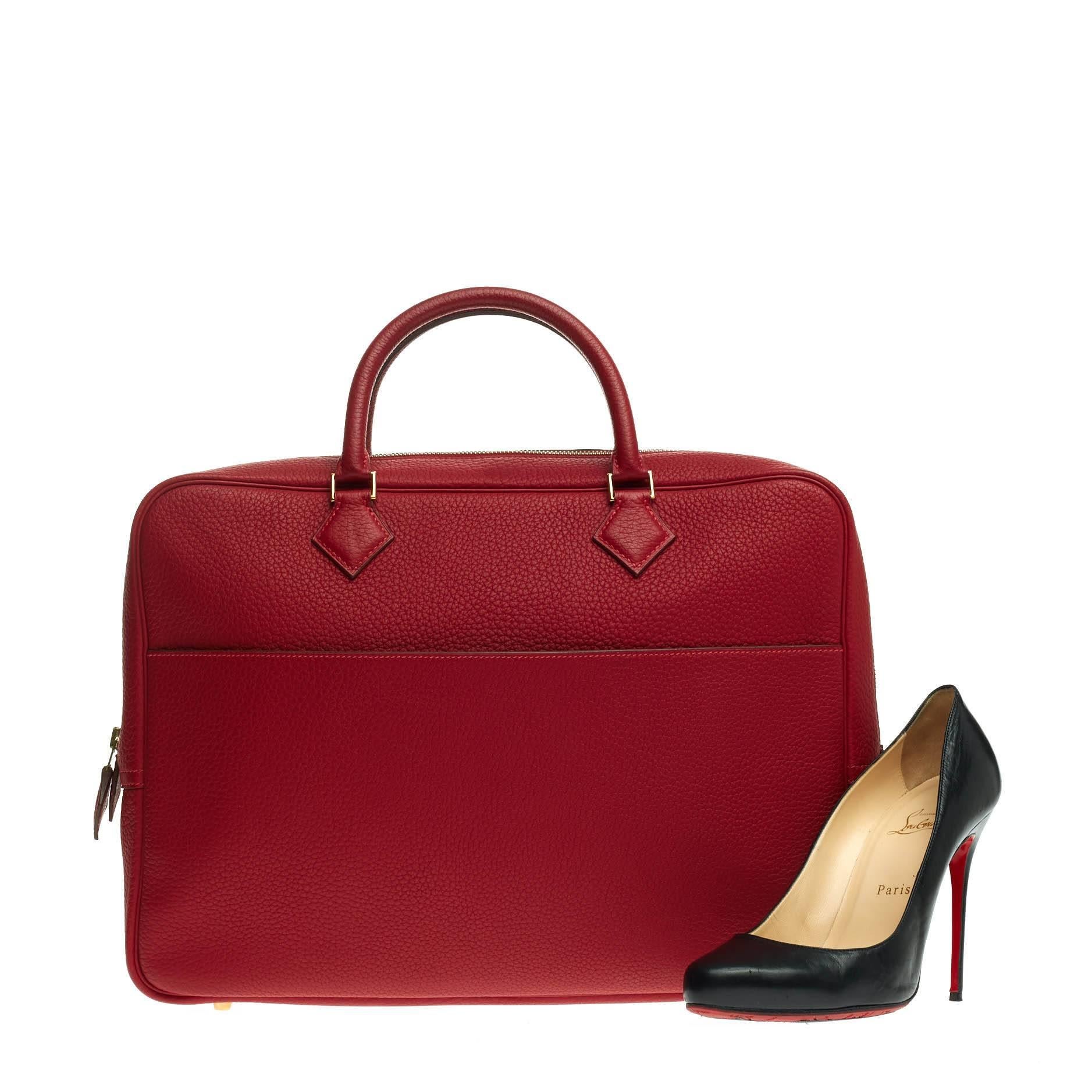 This authentic Hermes Plume Dog Clemence 38 showcases a simple yet chic design perfect for daily excursions and light traveling. Crafted in classic rouge vif red clemence leather, this discontinued, elegant travel piece features dual-rolled leather