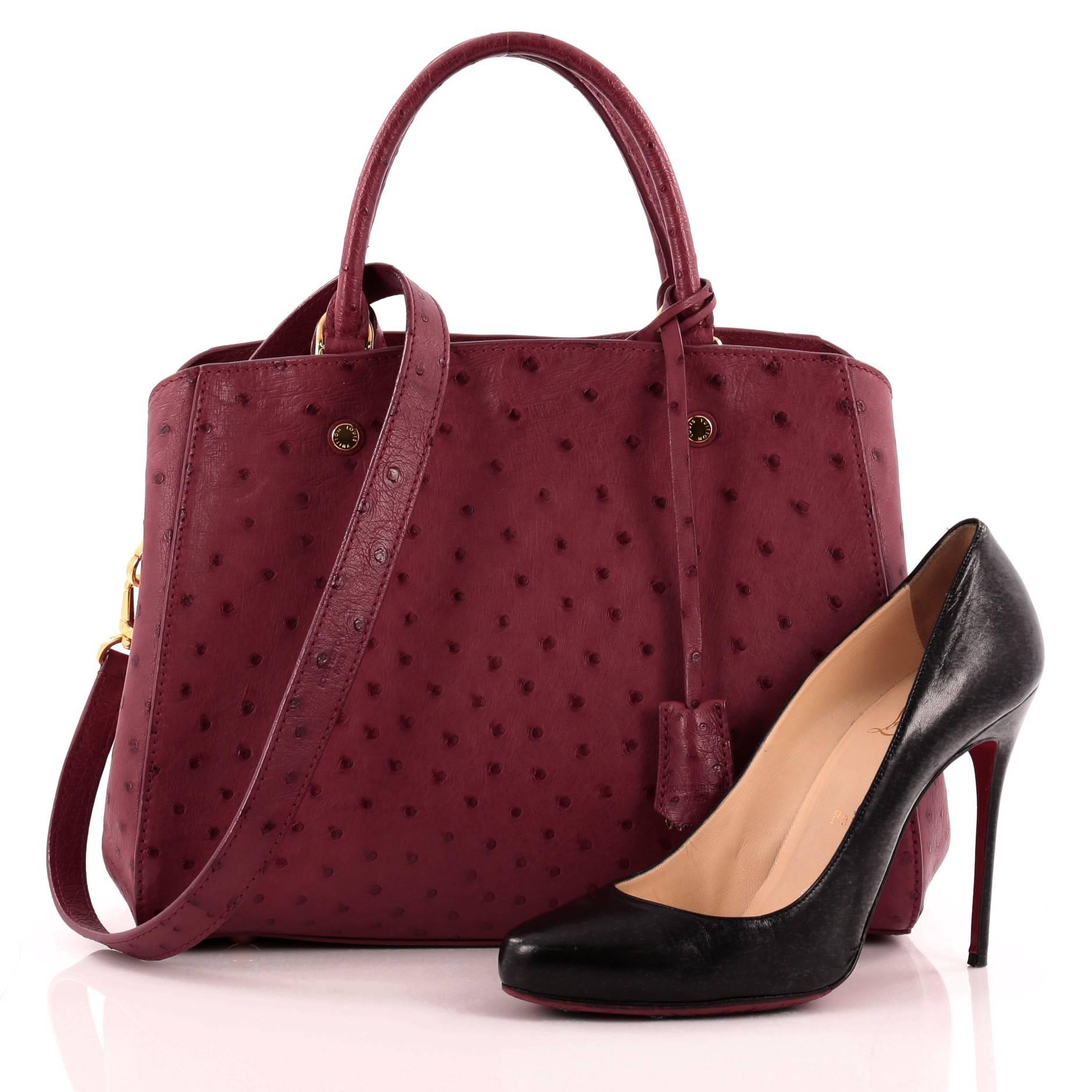 This authentic Louis Vuitton Montaigne Ostrich MM named after the glitzy Parisian is a hard-to-find collector's piece made for LV lovers. Crafted from fuschia genuine ostrich skin, this chic, luxurious tote features dual-rolled handles, removable