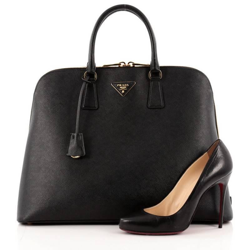 This authentic Prada Promenade Saffiano Leather Large is elegant in its simplicity and structure. Crafted in black saffiano leather, this sleek dome-shaped satchel features dual-rolled handles, protective base studs, Prada logo at the center and